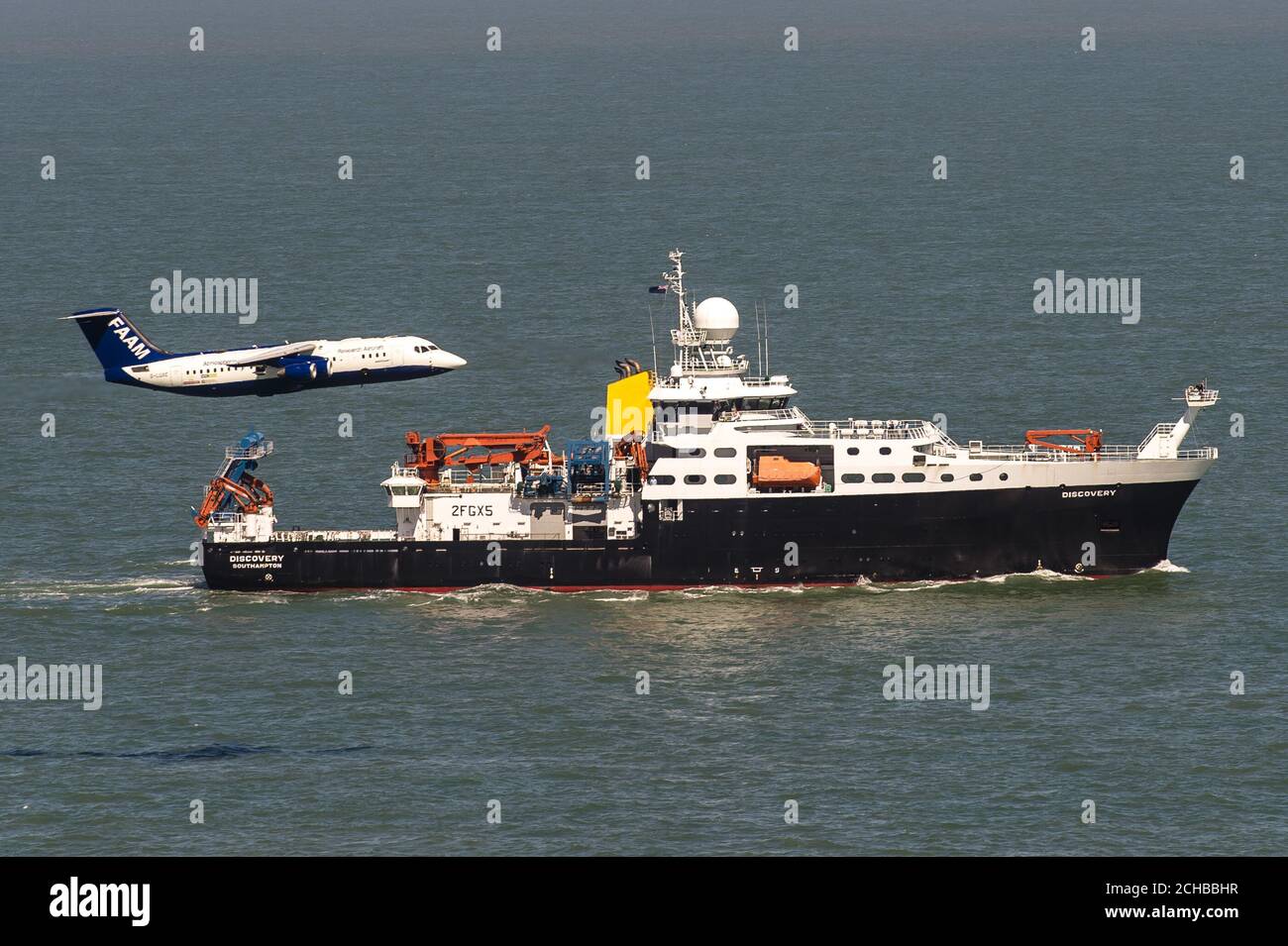 Das britische Natural Environment Research Council (NERC)-Flugzeug, genannt Facility for Airborne Atmospheric Measurements (FAAM) und Schiff RSS Discovery zusammen in der Solent vor der Isle of Wight und Portsmouth. Stockfoto