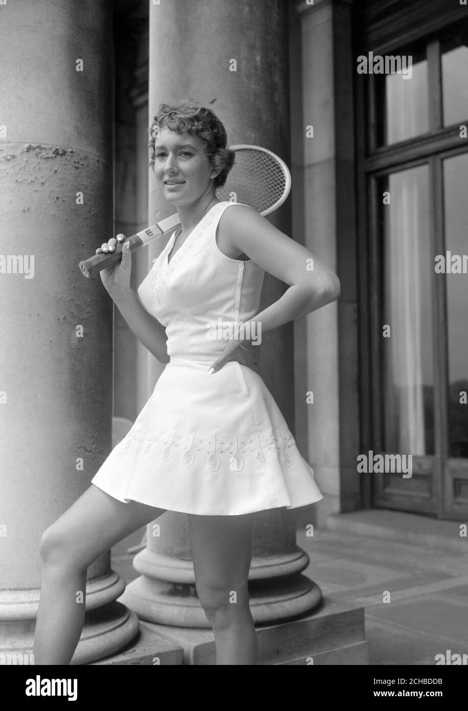 Schläger und Tennisbälle bilden das Stickmotiv des Kleides der amerikanischen Spielerin Sally Moore. Sie hat an der Pre-Wimbledon Tennis Party im Haus von Lady Crosfield in Highgate, London statt. Sally's Kittel zeigt in der Mitte jedes gestickten Schlägers ein Initial 'S' für Sally. Stockfoto