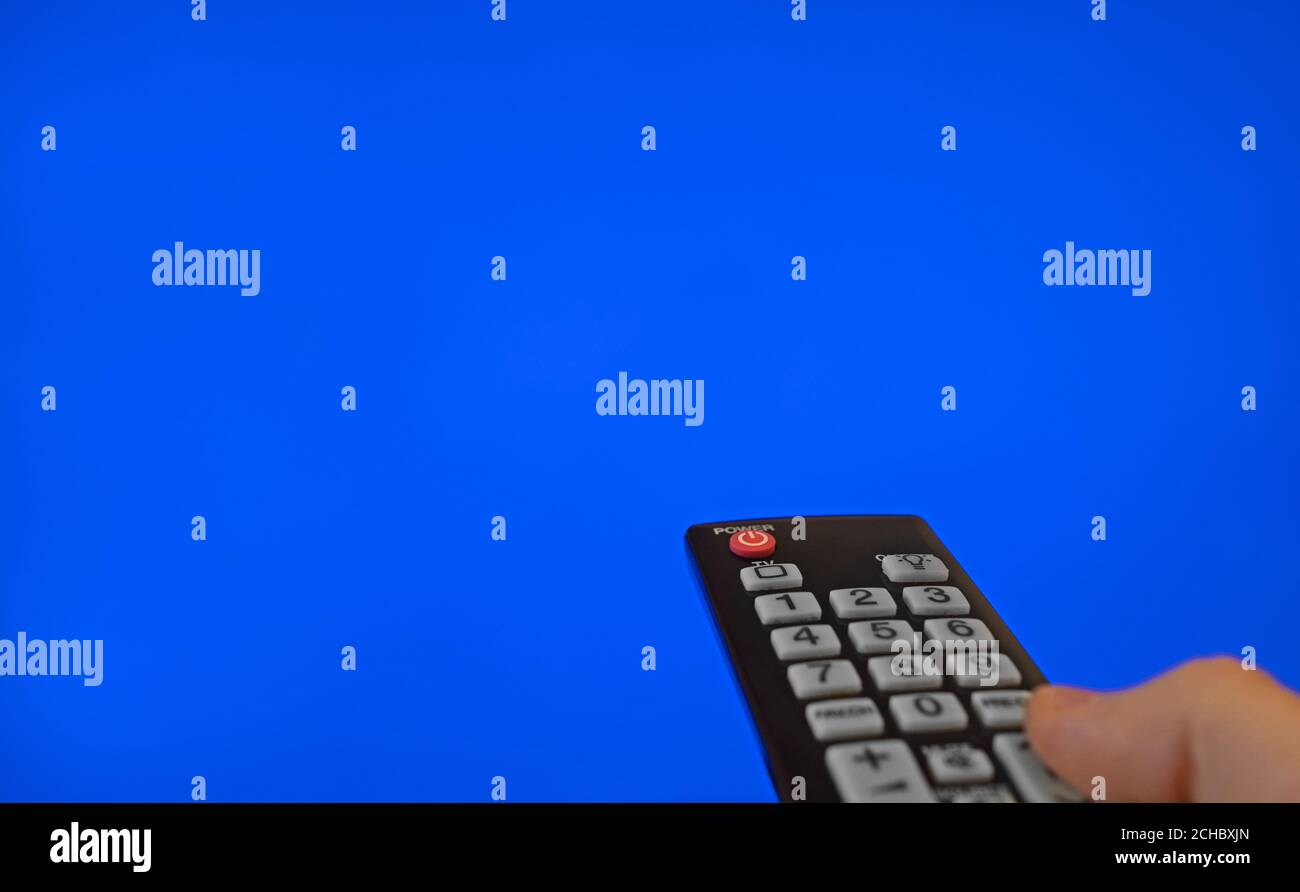Männliche Hand mit Fernbedienung, die auf den Fernsehbildschirm zeigt. Blaue Chroma-Taste. Stockfoto
