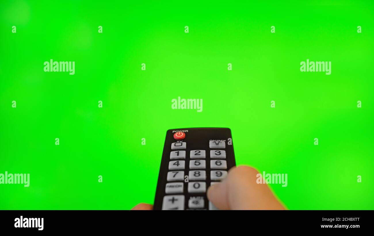 Männliche Hand mit Fernbedienung, die auf den Fernsehbildschirm zeigt. Grüne Chroma-Taste. Stockfoto