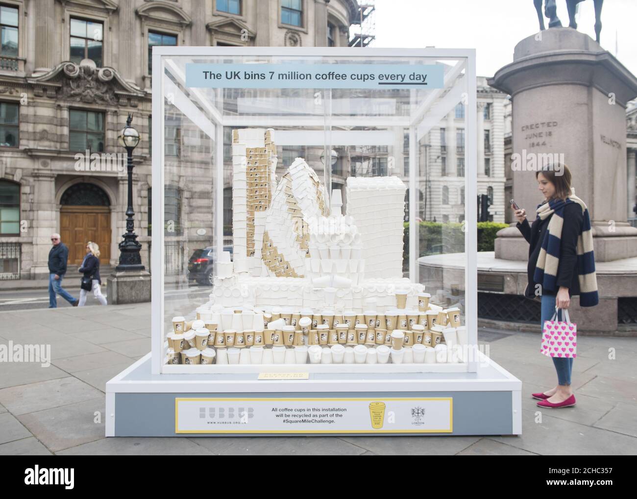Ein Mitglied der Öffentlichkeit macht ein Foto von einer riesigen Tasse Kaffee in London Skyline Skulptur, enthüllt für die Einführung der Square Mile Challenge, das größte britische Kaffeetassen Recycling-Programm an der Royal Exchange in London. Stockfoto