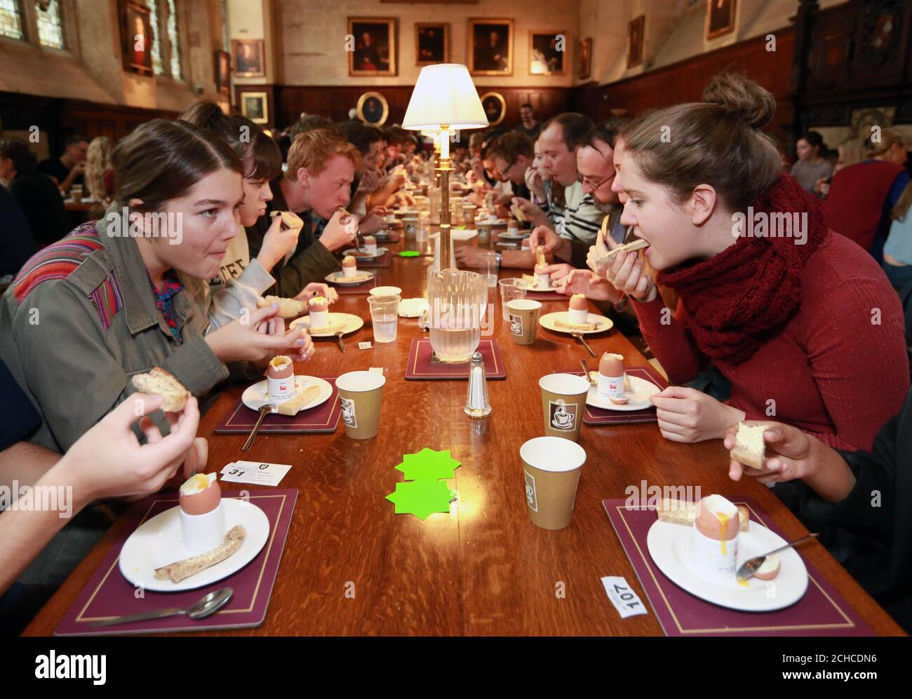 183 Universitätsstudenten, Mitarbeiter und Anwohner der Exeter College Dining Hall in Oxford brechen den Rekord für „die meisten Menschen, die Eiersoldaten gleichzeitig eintauchen“, der zuvor auf 178 eingestellt war. Stockfoto