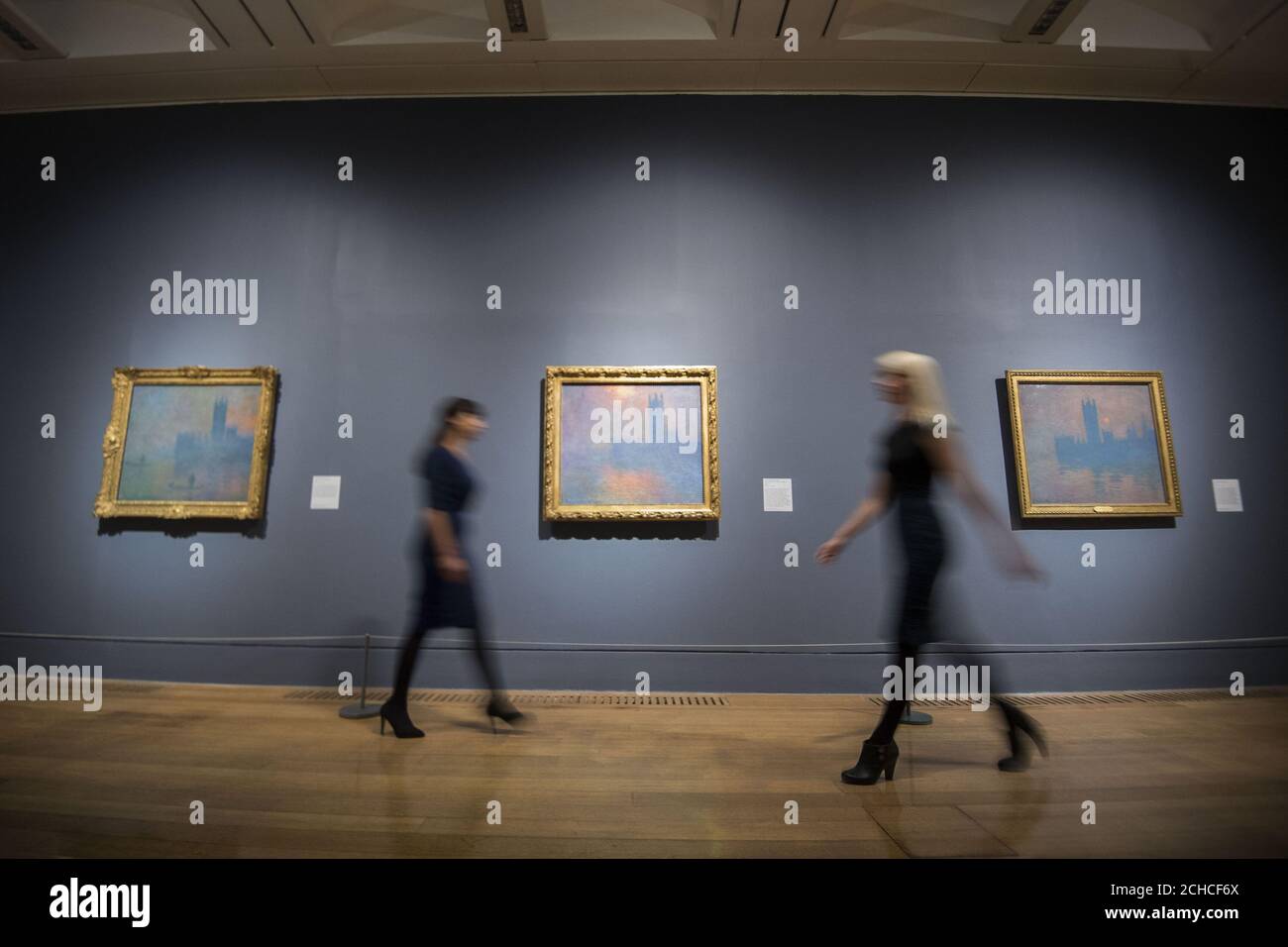 Mitarbeiter gehen bei einem Fotocall für die Ausstellung EY an den Gemälden der Houses of Parliament von Claude Monet vorbei: Impressionisten in London, French Artists in Exile (1870-1904), die die größte Anzahl von Monets Houses of Parliament Serie in Großbritannien seit über vierzig Jahren in der Tate Britain, London zu vereinen. Stockfoto Mitarbeiter gehen bei einem Fotocall für die Ausstellung EY an den Gemälden der Houses of Parliament von Claude Monet vorbei: Impressionisten in London, French Artists in Exile (1870-1904), die die größte Anzahl von Monets Houses of Parliament Serie in Großbritannien seit über vierzig Jahren in der Tate Britain, London zu vereinen. Stockfoto
