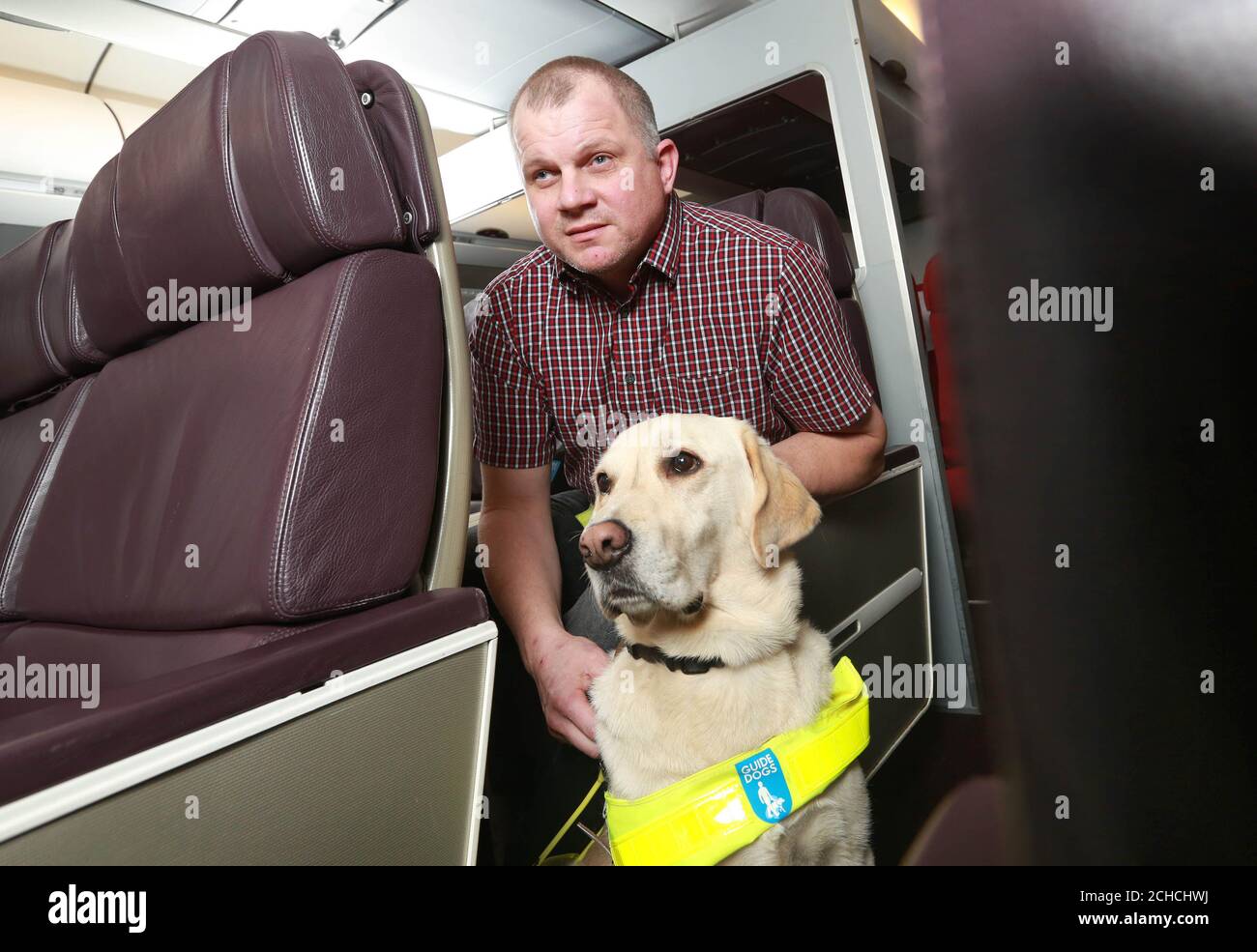 Paul Smith, Blindenführhunde und Blindenführhund Pedro probiert eine neue Reihe von Bordtechnologien (IFE) aus, die speziell für sehbehinderte Kunden an Bord von Virgin Atlantic Services in Gatwick in West Sussex entwickelt wurden. Stockfoto