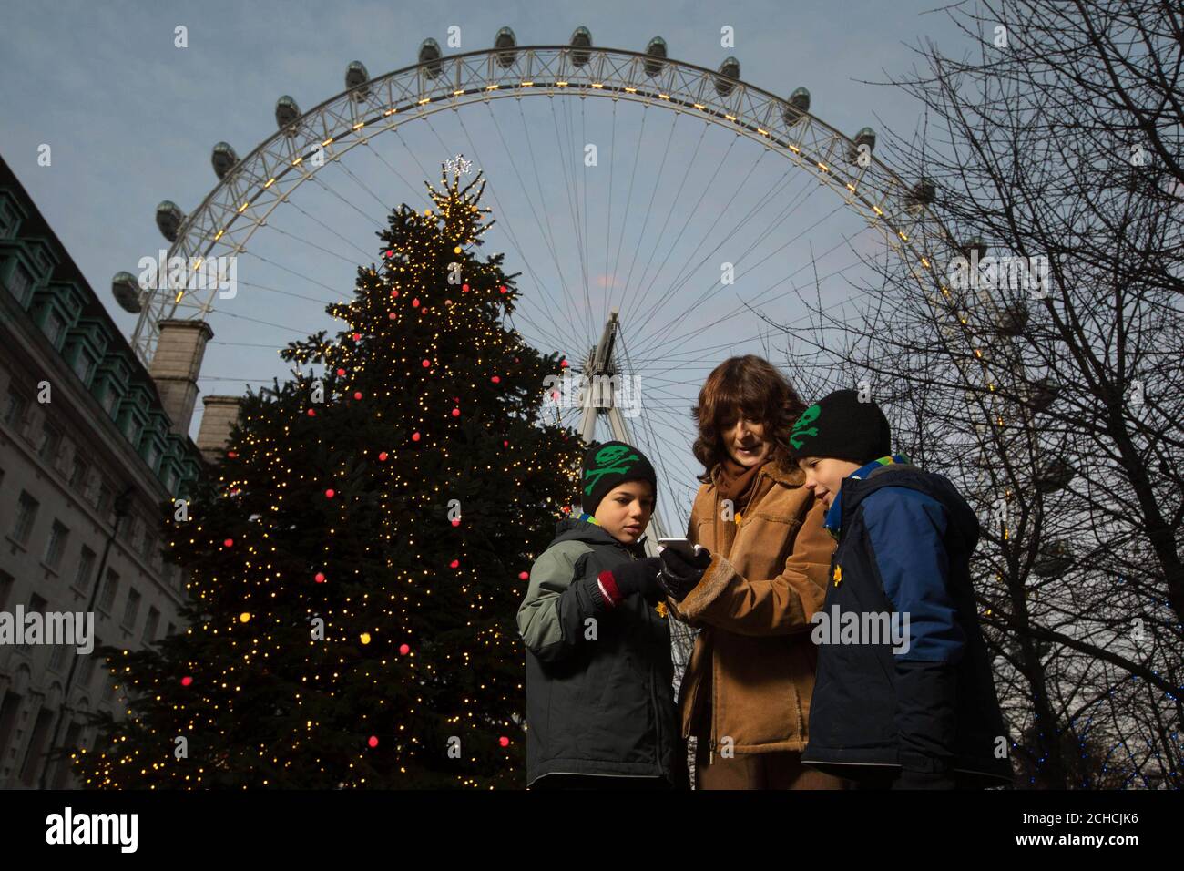 Paola Domizio mit ihren Söhnen Sasha (links) und Aron Rose, beide neun Jahre alt, lebt mit einer unheilbaren Krankheit nutzt #lightupxmas auf Twitter für Marie Curies „Memory Tree“, der dann die Lichter auf dem Baum heller werden lässt, Southbank, London. Stockfoto