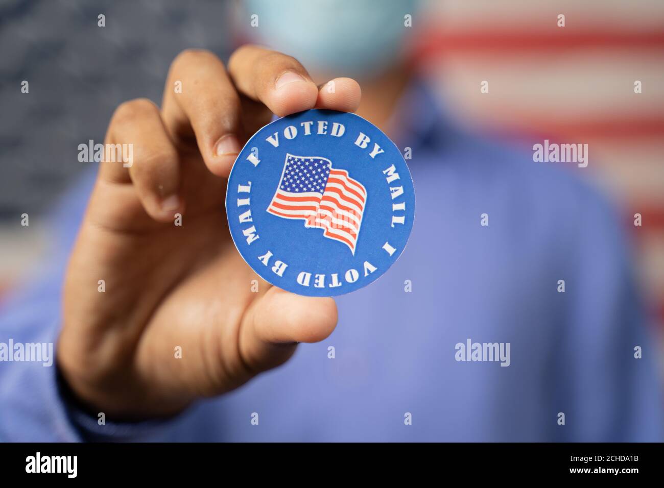 Nahaufnahme der Hände, die zeigen, dass ich per Mail-Aufkleber mit USA-Flagge als Hintergrund gestimmt habe - Konzept der US-Wahl, Mail-in-Abstimmung oder per Post abstimmen Stockfoto