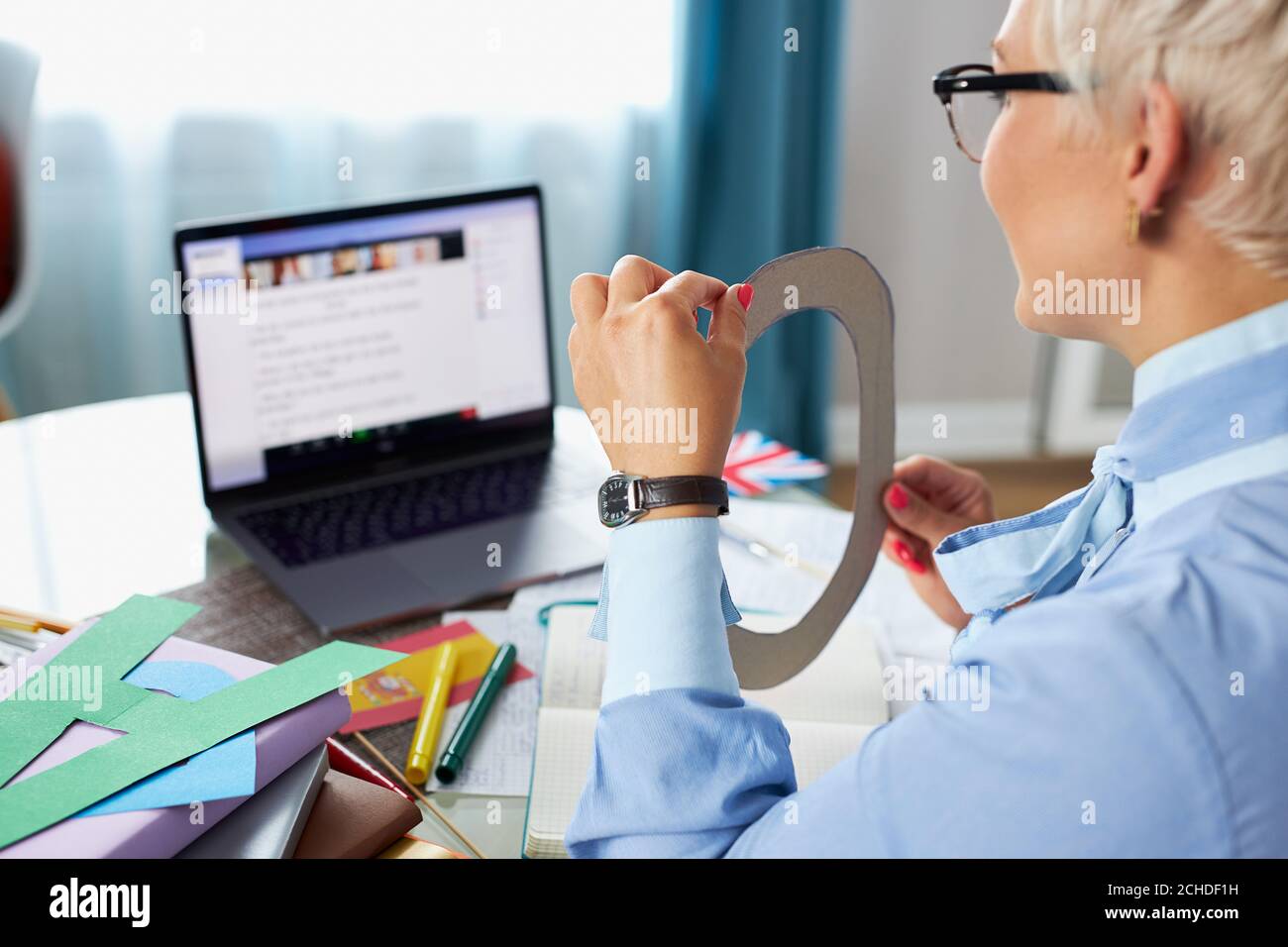 Fleißige kurzhaarige Lehrer halten Unterricht online, zeigen Karton geschnitten Briefe an webcamera. Online-Bildung, Lernen. E-Learning-Konzept Stockfoto