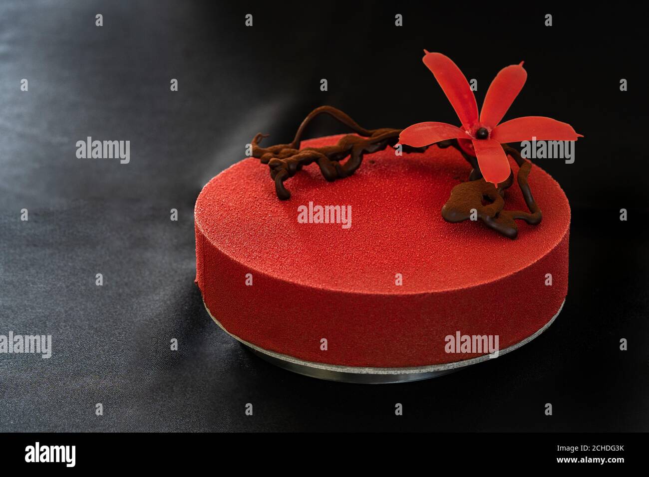 Rote Geburtstagstorte mit Schokoladenblume isoliert auf schwarzem Hintergrund. Speicherplatz kopieren. Nahaufnahme. Hochwertige Fotos Stockfoto