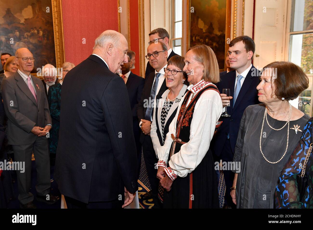 König Harald V. von Norwegen trifft Gäste beim hundertjährigen Empfang der Anglo-Norse Society im Naval and Military Club im Zentrum von London. Stockfoto