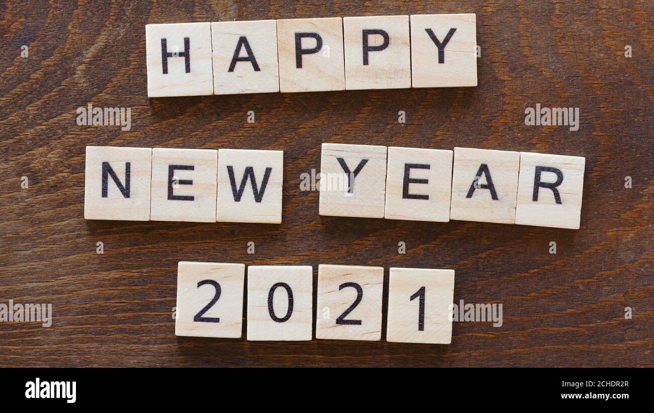 Geschrieben 'glückliches neues Jahr 2021' mit hellen Holzbuchstaben auf Dunkles Holz Stockfoto