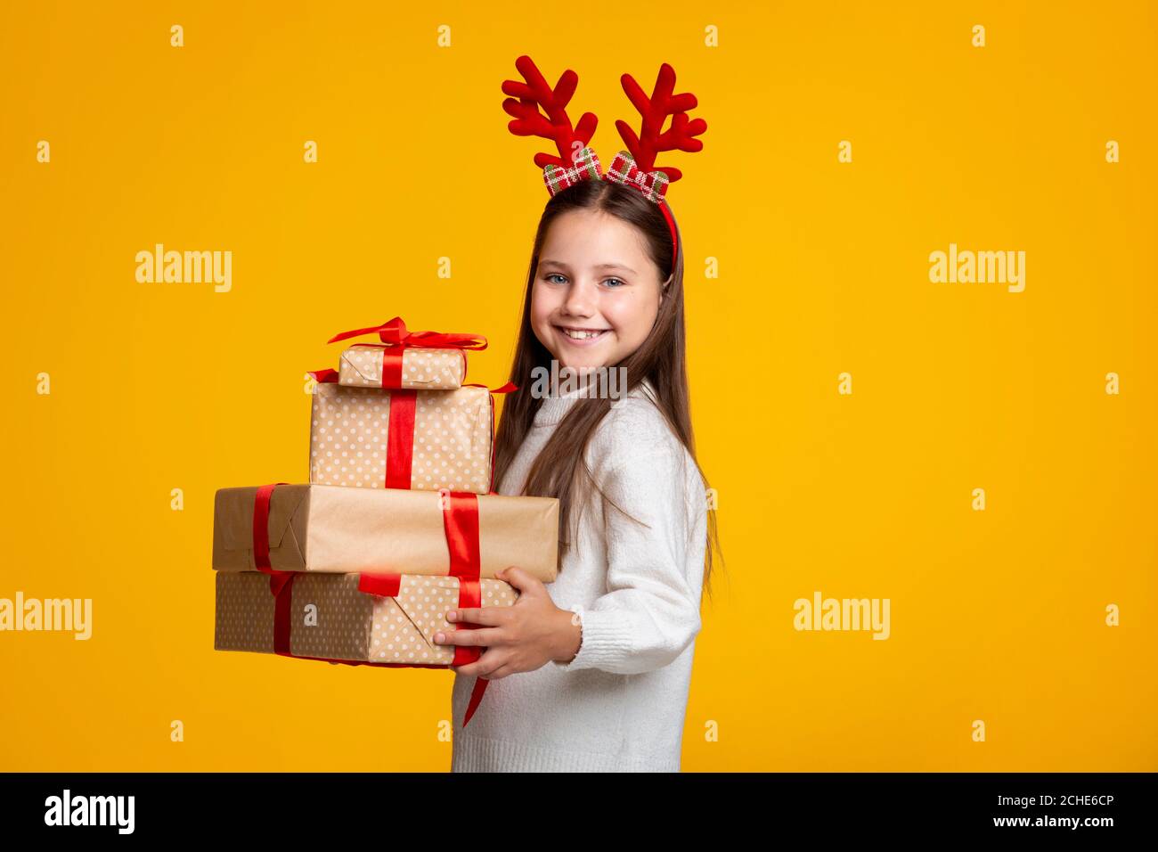 Weihnachtsgeschenke. Glückliches Kind mit Hörnern und in Pullover hält eine Menge von Boxen mit Geschenken Stockfoto
