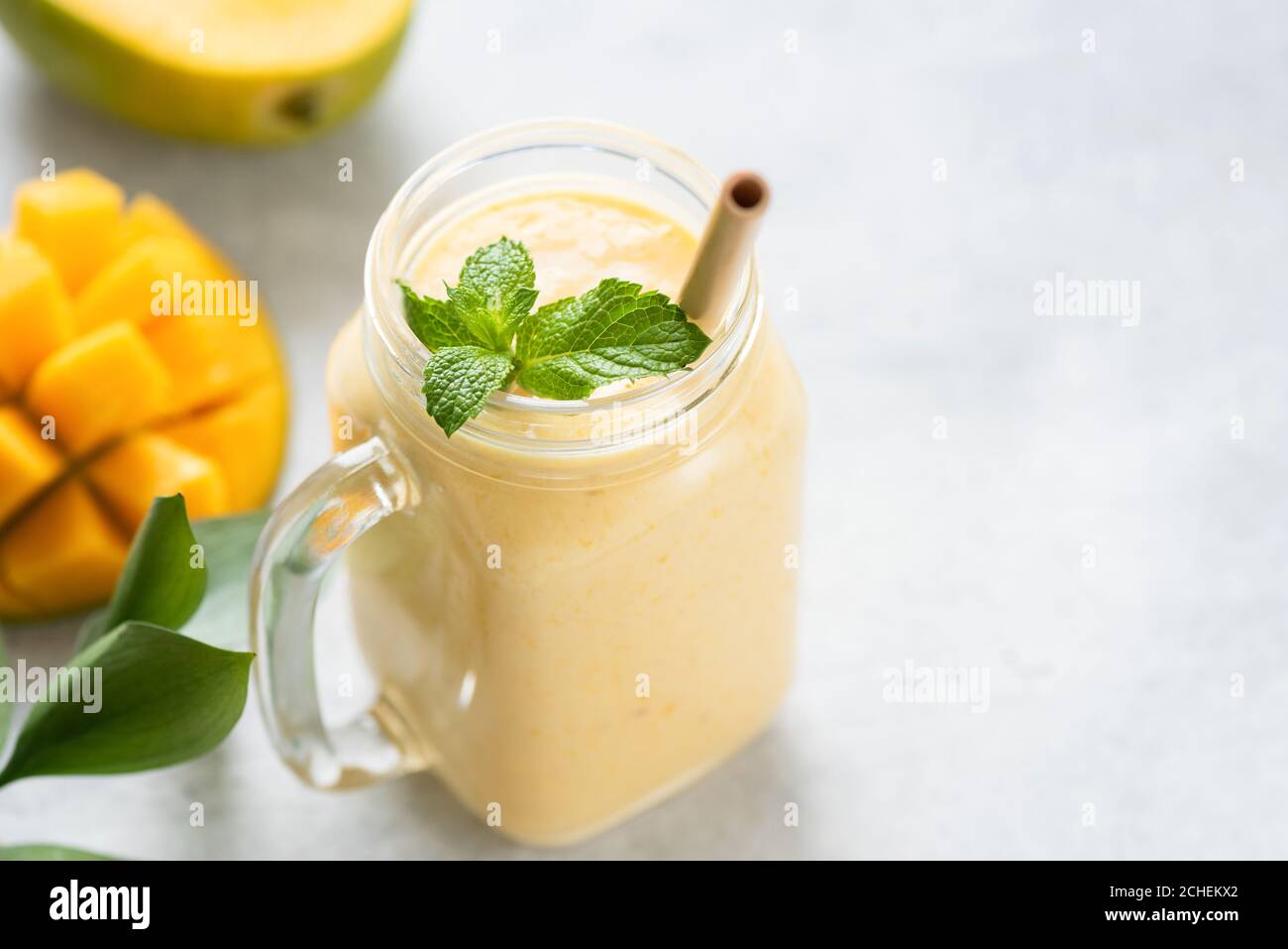 Mango Lassi in einem Glas auf grauen Beton Hintergrund Tisch, kopieren Platz für Text oder Design. Mango Joghurt Smoothie Stockfoto