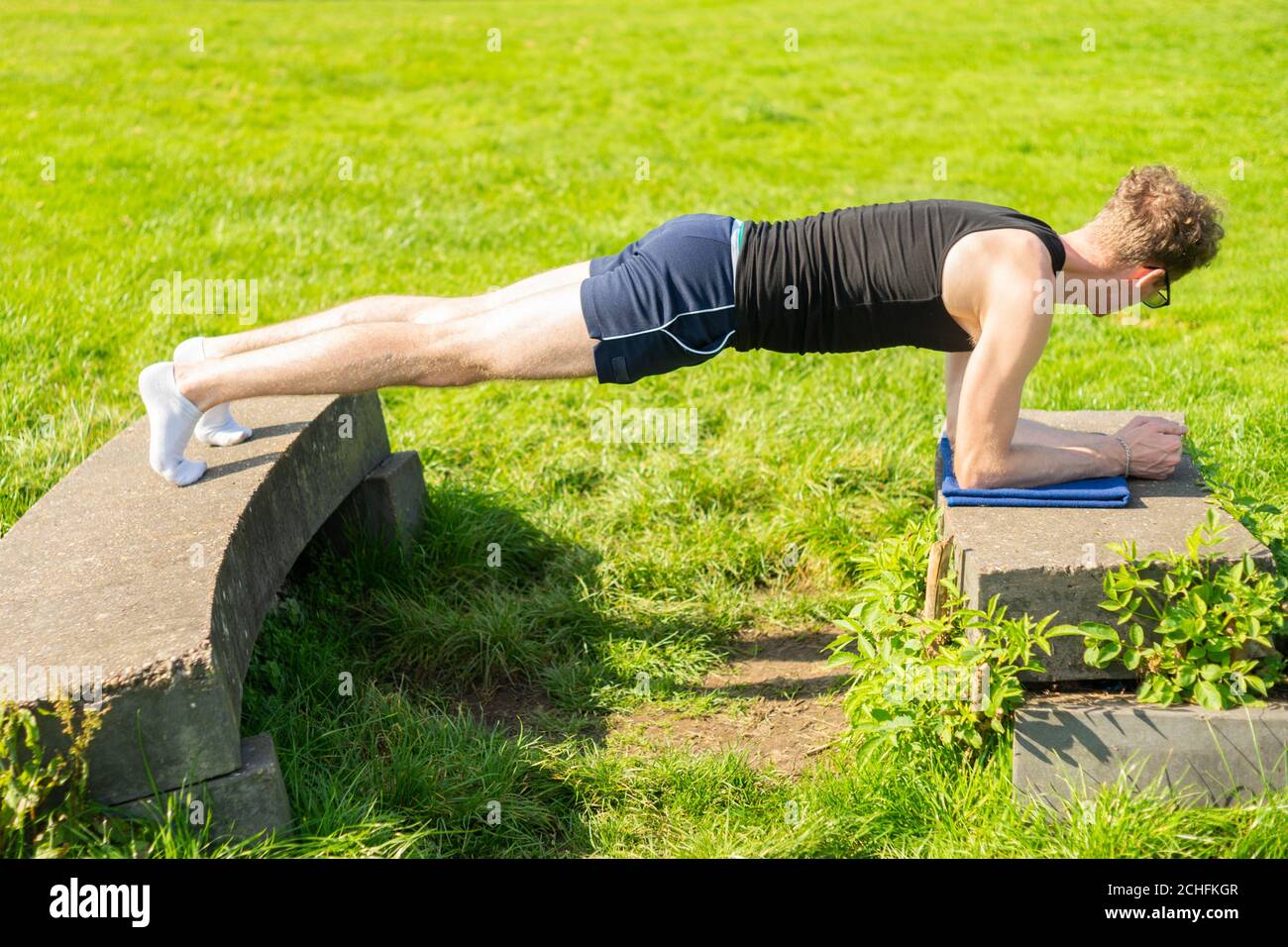 Junger Mann, der Plank-Übung in einer Außenumgebung durchführt. Stärkung der Kernmuskulatur, Bewegung, fit halten, Gesundheit Stockfoto