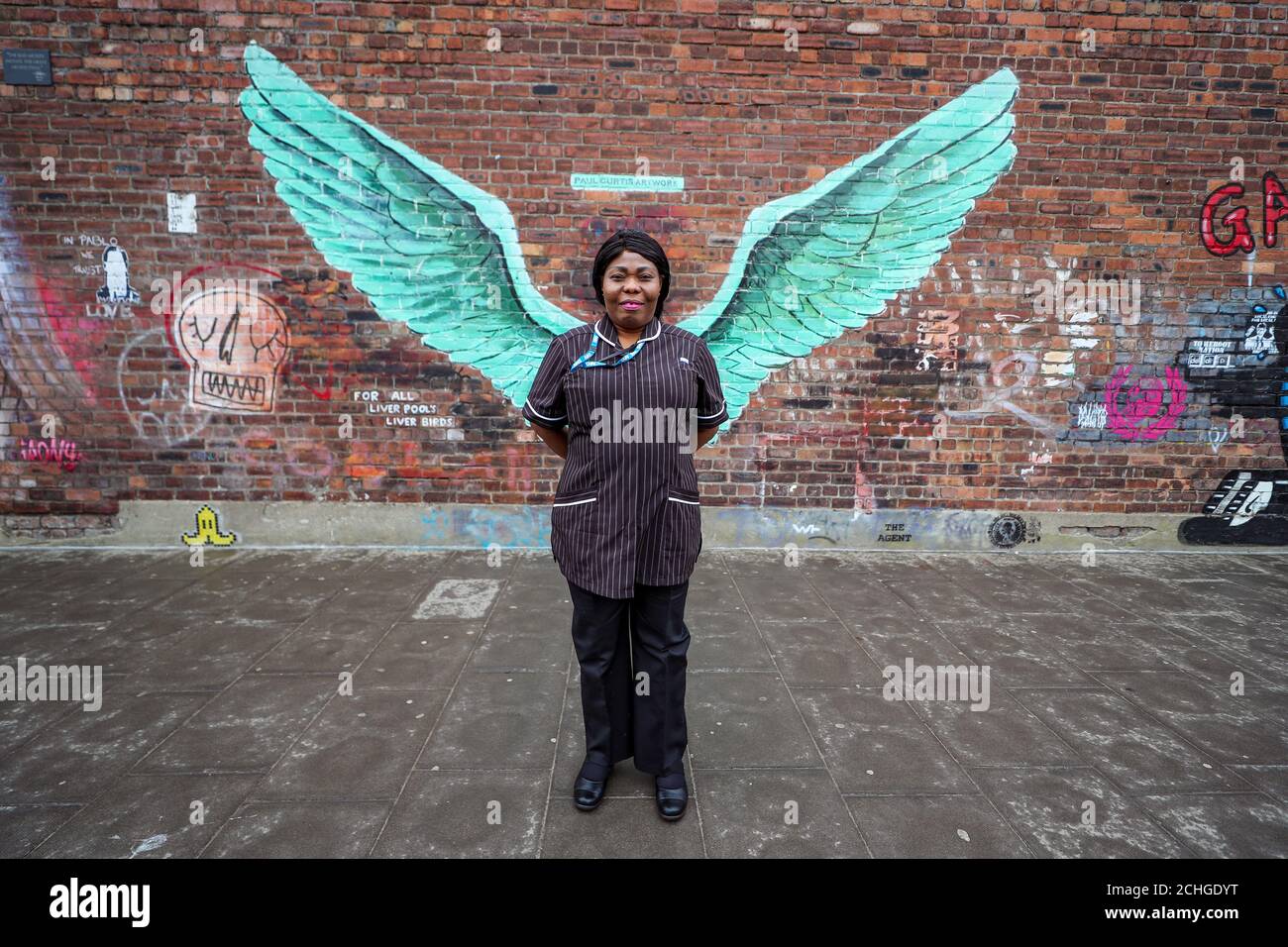 Susan Tay, Community Matron bei Mersey Care NHS, steht vor den "Liver Bird Wings", einem Kunstwerk von Paul Curtis an einer Wand im Baltischen Dreieck von Liverpool. Stockfoto