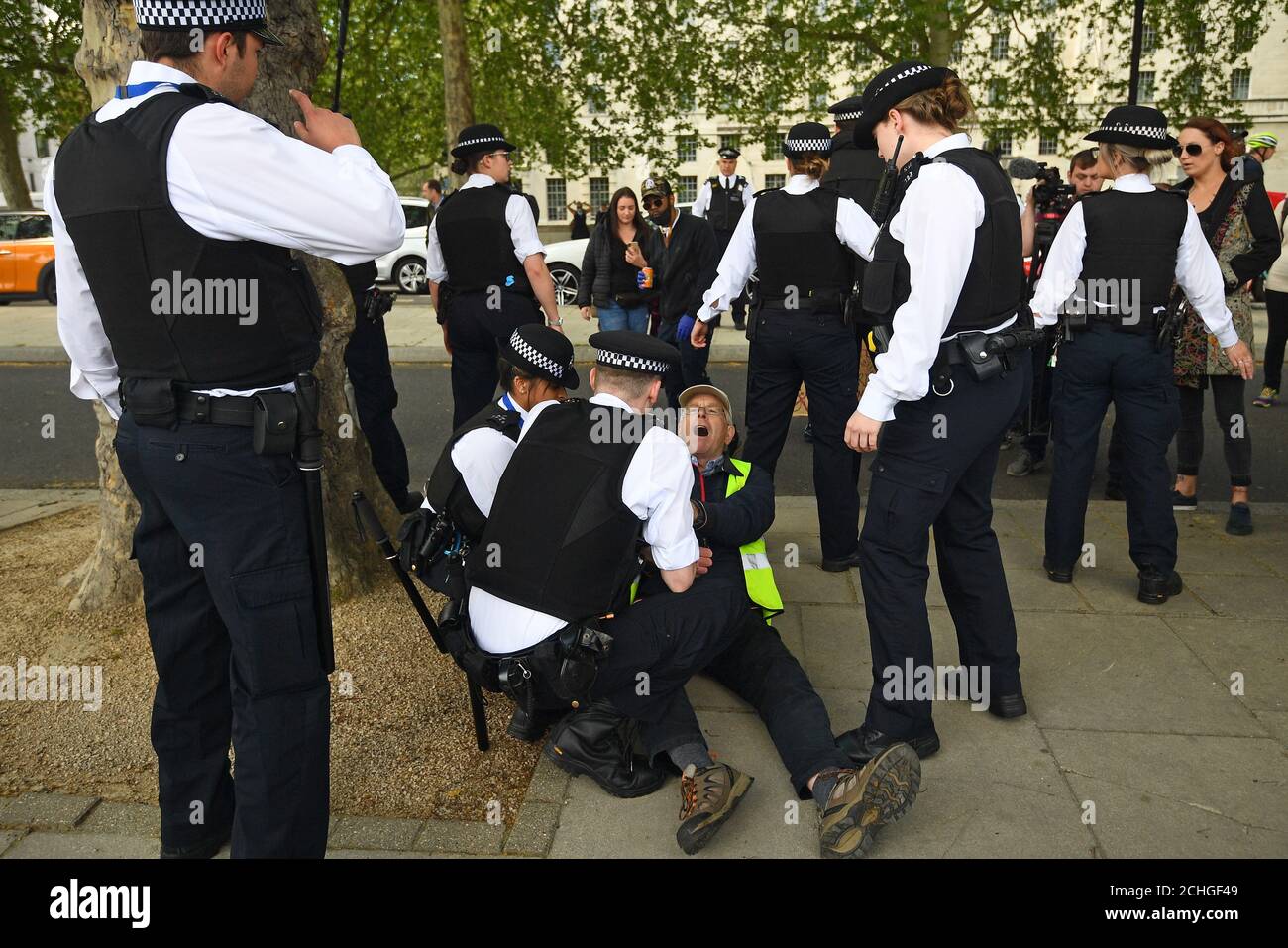 Ein Mann wird von Polizisten während eines Protestes gegen die Covid-19-Sperre vor New Scotland Yard in London festgehalten. Stockfoto
