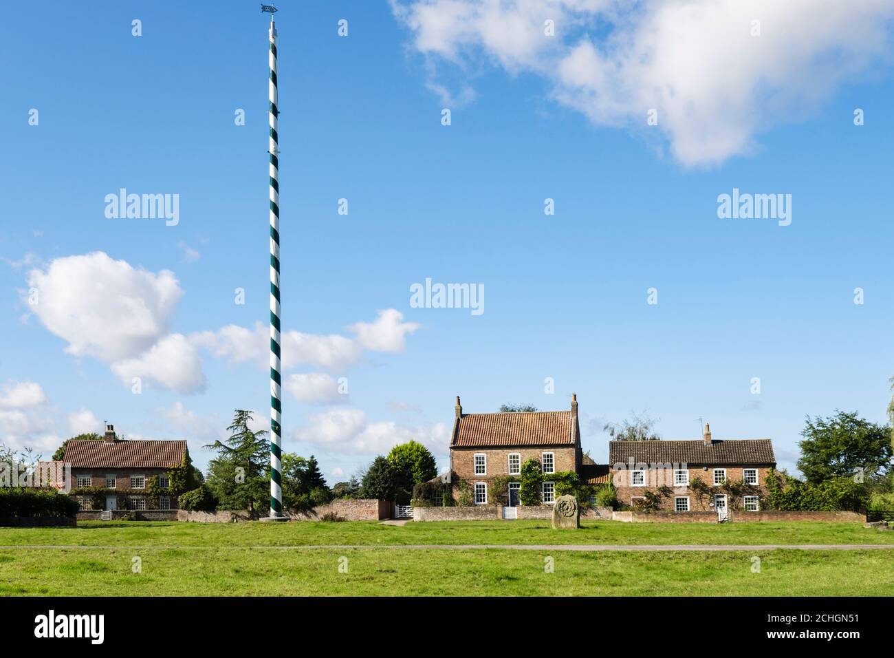 Maibaum mit altem Haus mit Blick auf ein Landdorf grün. Nonne Monkton, York, North Yorkshire, England, Großbritannien Stockfoto