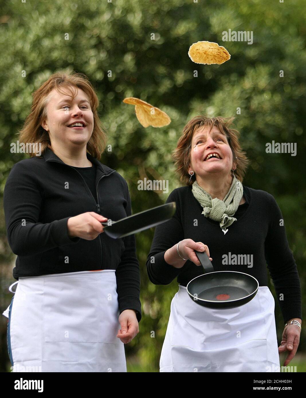 Die Lebensmittelberater Helen Woods (links) und Maureen Porteous demonstrieren am 5. Februar vor dem Shrove Tuesday am Soho Square in London ihre Fähigkeiten beim Pfannkuchenflippen. Stockfoto