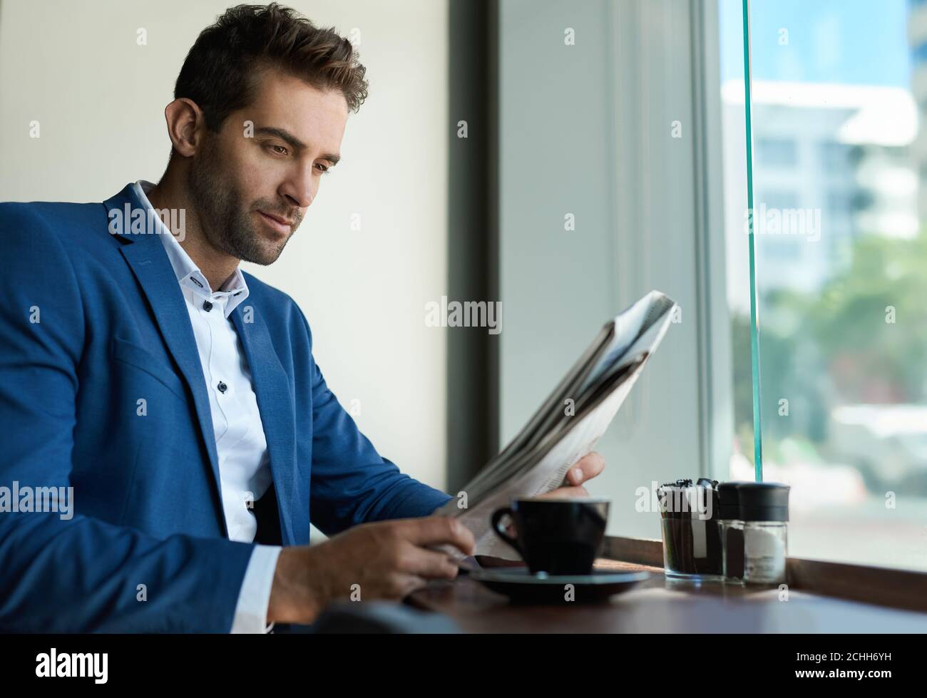 Geschäftsmann sitzt in einem Café und liest eine Zeitung Stockfoto