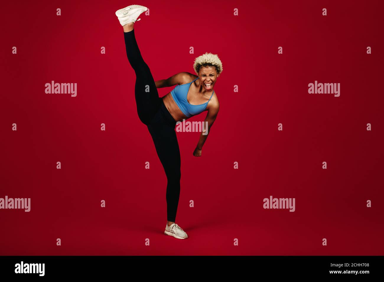 afroamerikanische Fitness-Frau, die auf Flexibilität tut Dehnübungen. Fit Frau dabei Training vor kastanienbraunen Hintergrund. Stockfoto