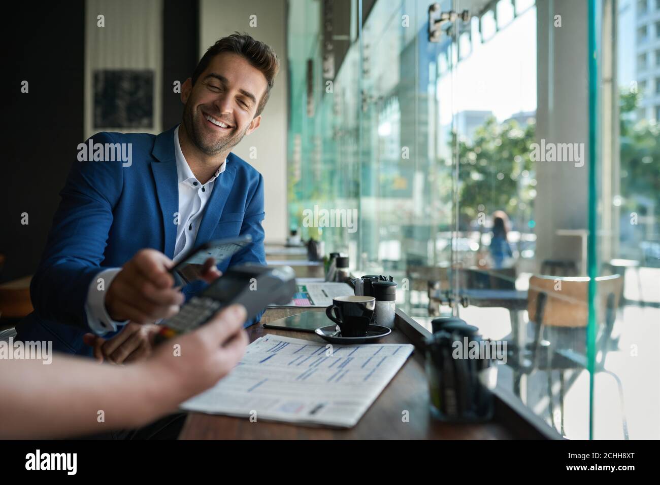 Lächelnder Mann, der seinen Kellner mit nfc-Technologie bezahlt Stockfoto