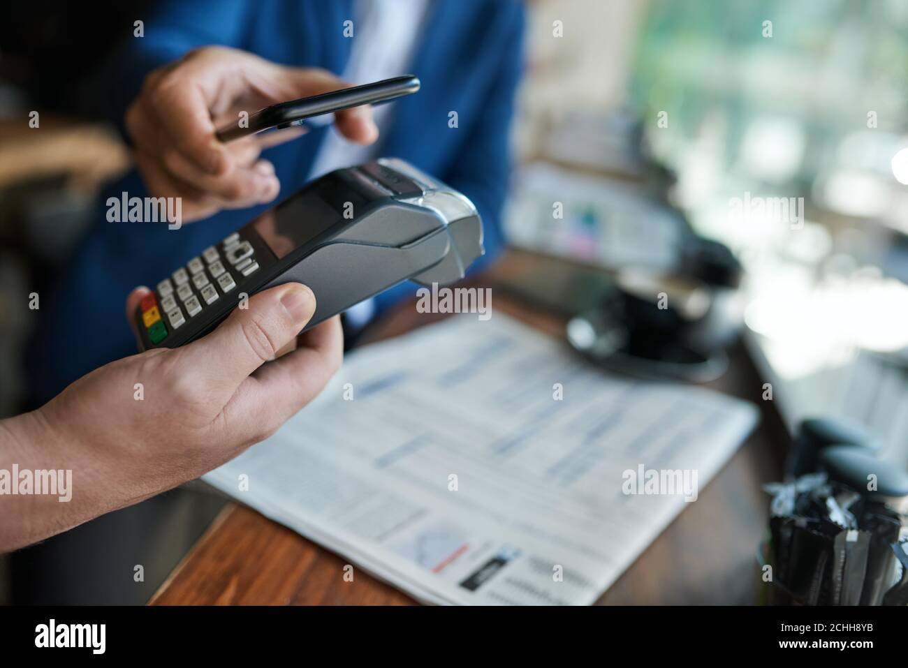 Cafe-Kellner, der ein nfc-Terminal mit dem Telefon eines Kunden verwendet Stockfoto