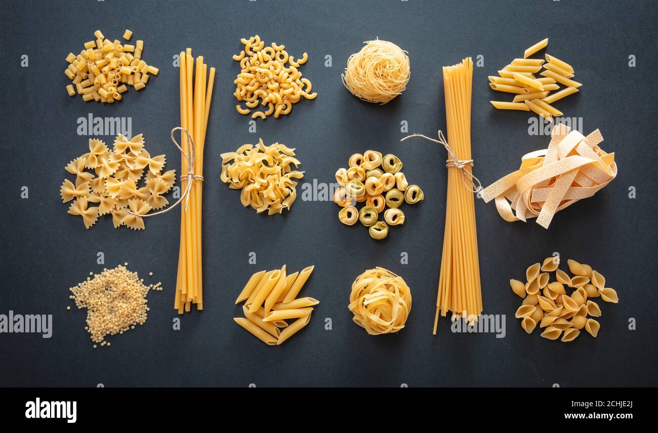Pasta-Kochkonzept. RAW Pasta Formen Vielfalt flach lag auf schwarzem Hintergrund, Draufsicht Stockfoto