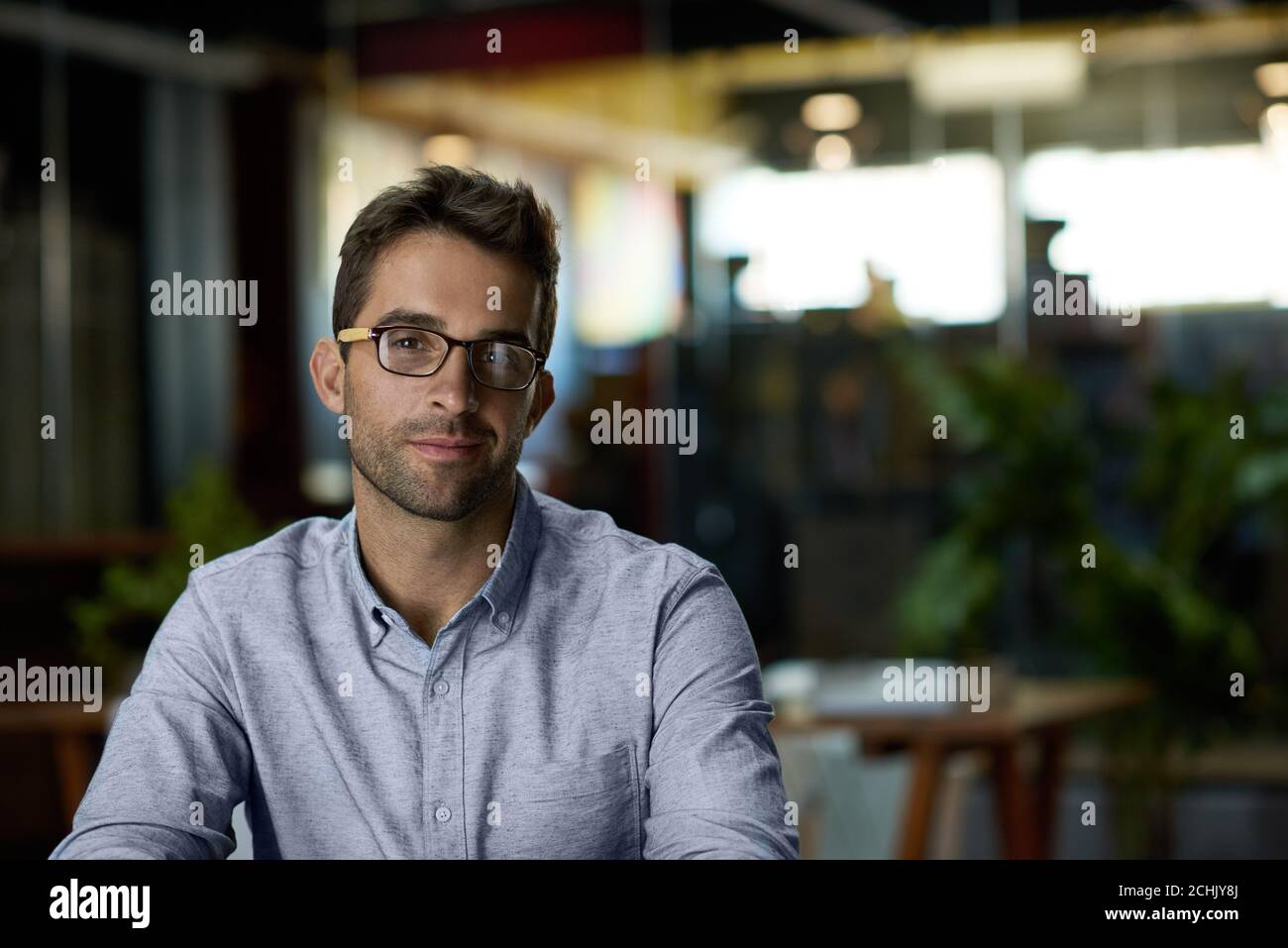 Selbstbewusster junger Geschäftsmann, der nach Geschäftsschluss in einem Büro sitzt Stockfoto