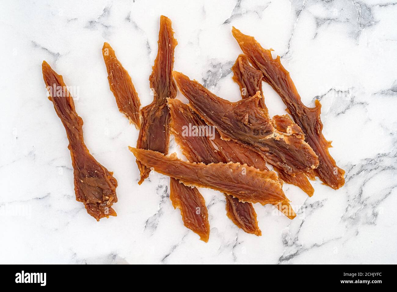 Leckeres Hundegeschenk, getrocknete Entenkeeper auf weißem Marmorboden. Stockfoto