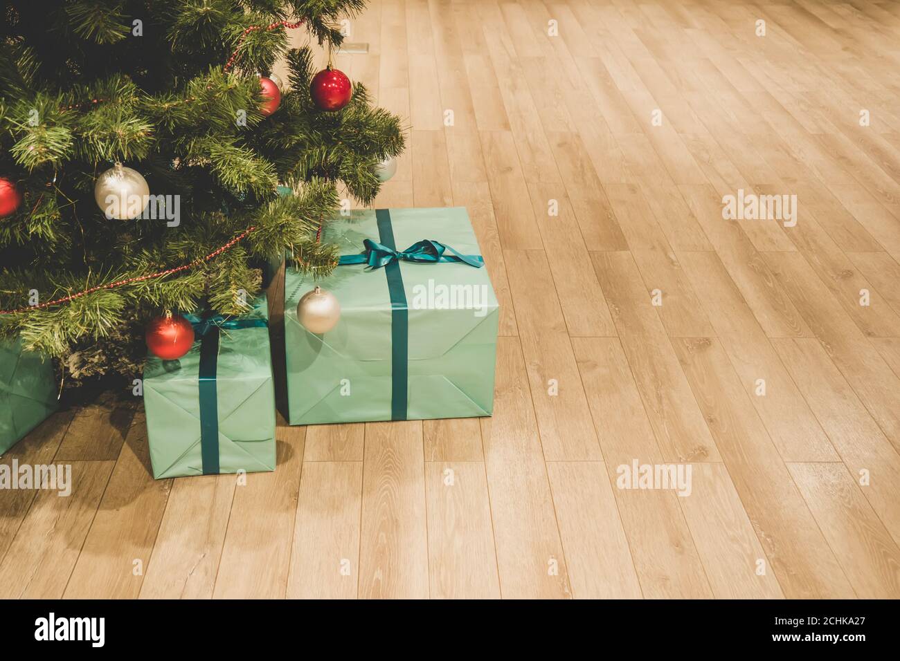 Weihnachtsbaum mit Dekorationen und Geschenke unter ihm innen. Blaue Schachtel auf dem Boden unter dem Weihnachtsbaum. Geschenke vom Weihnachtsmann verpackt in einem Stockfoto