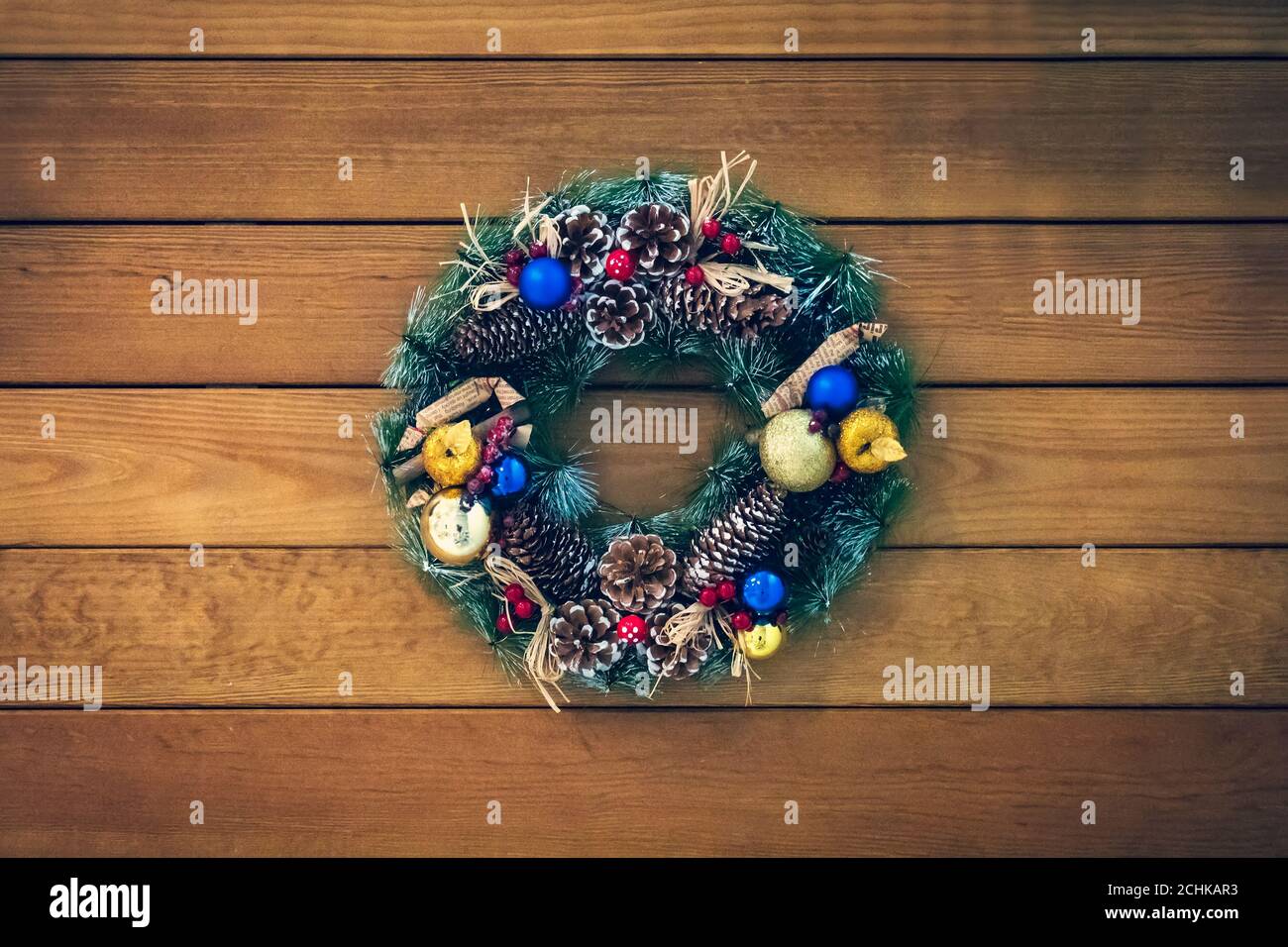 Weihnachtskranz aus Zapfen, Fichtenzweigen und Beeren, Neujahrsschmuck. Schöner Fichtenkranz mit Zapfen, Kugeln und Früchten. Stockfoto