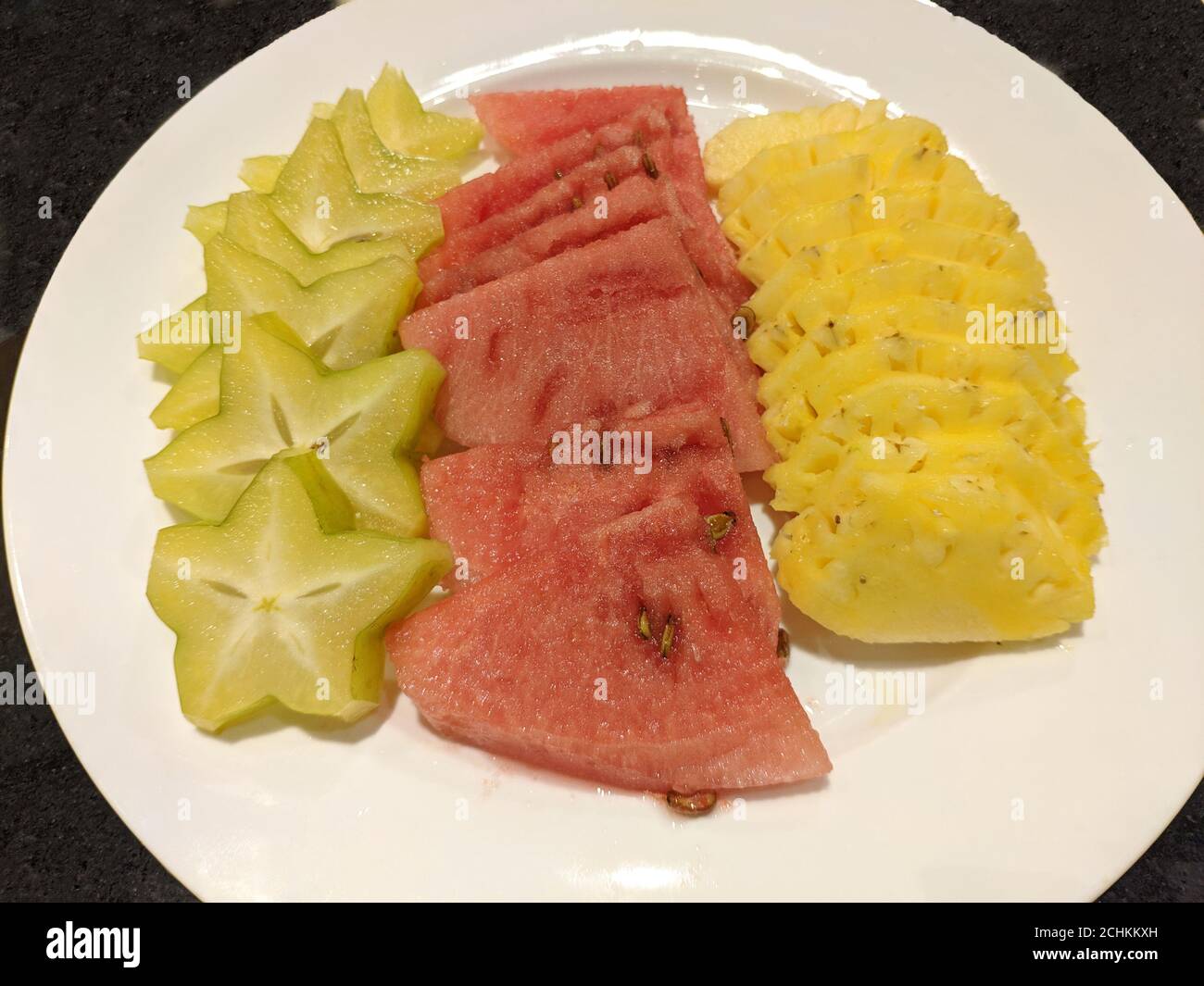 Frische rote Wassermelone, gelbe Ananas und grüne Karambola auf dem weißen Teller zum Essen Stockfoto