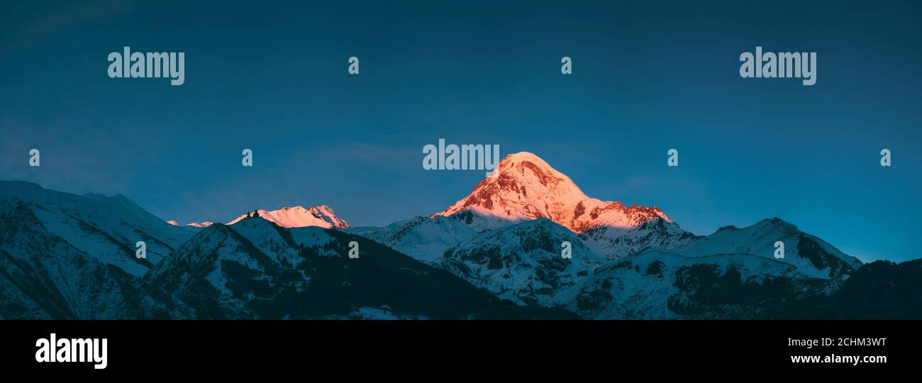 Georgien. Mount Kazbek Bedeckt Schnee im Winter Sonnenaufgang. Morgendämmerung farbige Gipfel des Berges in rosa-orange Farbe. Super Winter georgischen Natur Stockfoto
