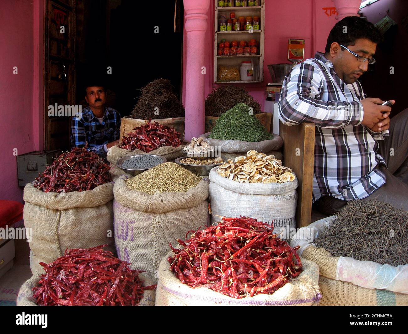 Lebensmittelgeschäft in einer zentralen Straße von Bikaner, Rajasthan. Zwei Verkäufer sind in der Nähe von großen Tüten mit indischem Essen sichtbar. Stockfoto