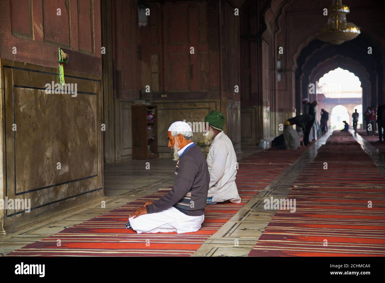 Delhi, Indien: Jama Masjid Moschee. Indische Männer beten vor einer Wand. Stockfoto