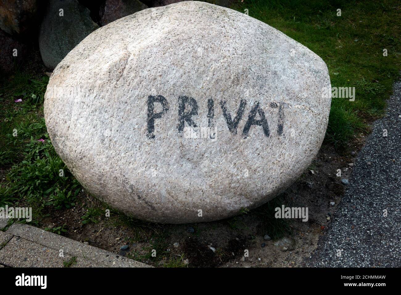 Heller Granit erratischer Block mit der verblassten Inschrift privat Markieren Sie das Ende des öffentlichen Bereichs Stockfoto