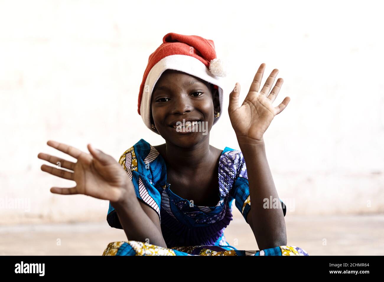 Wunderschöne afrikanische Schulmädchen posiert für Weihnachten mit Hut und Hände Öffnen Stockfoto