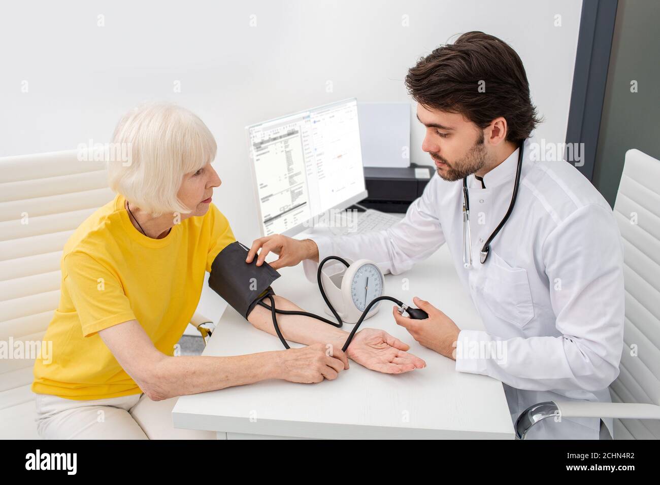 Arzt zur Messung des arteriellen Blutdrucks einer Seniorin in der modernen Klinik. Stockfoto