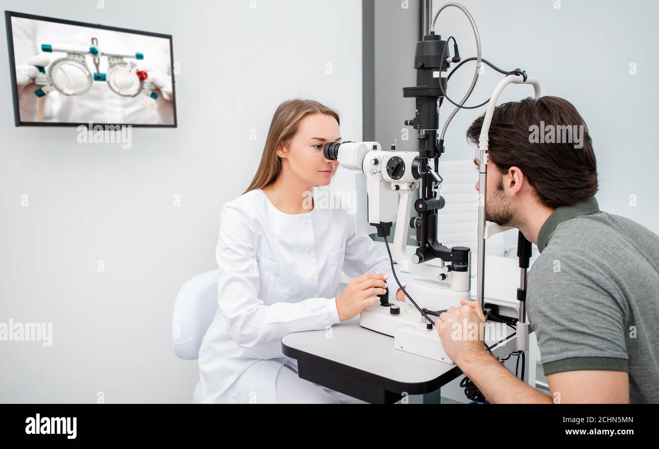 Augenarzt Frau macht eine diagnostische Sehprüfung erwachsenen Mann. Augenuntersuchung und diagnostische Augenerkrankungen Stockfoto