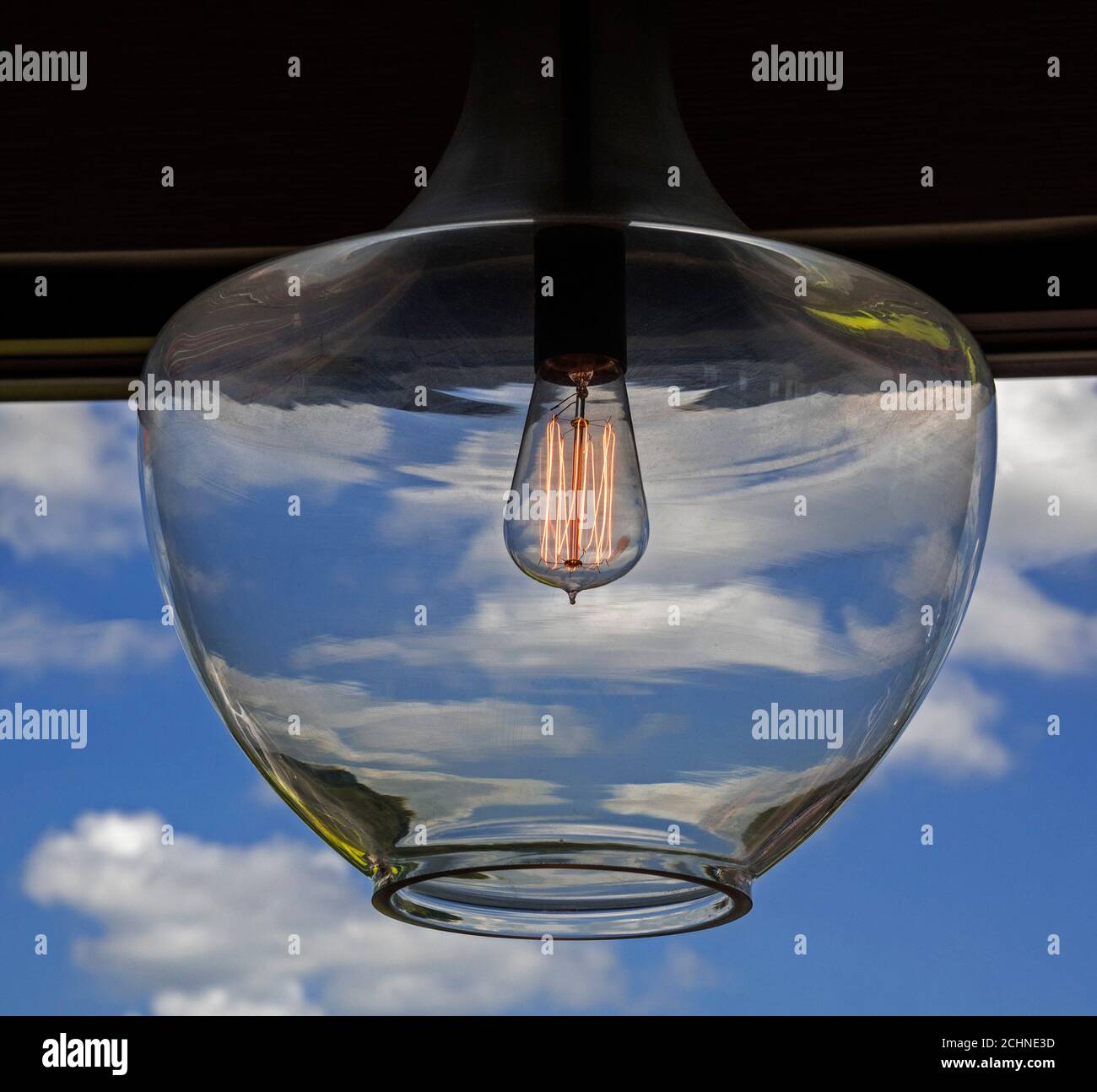 Von Thomas Edison inspirierte Glühbirne im Retro-Look erstrahlt in einem Restaurant durch einen hängenden Globus. Stockfoto