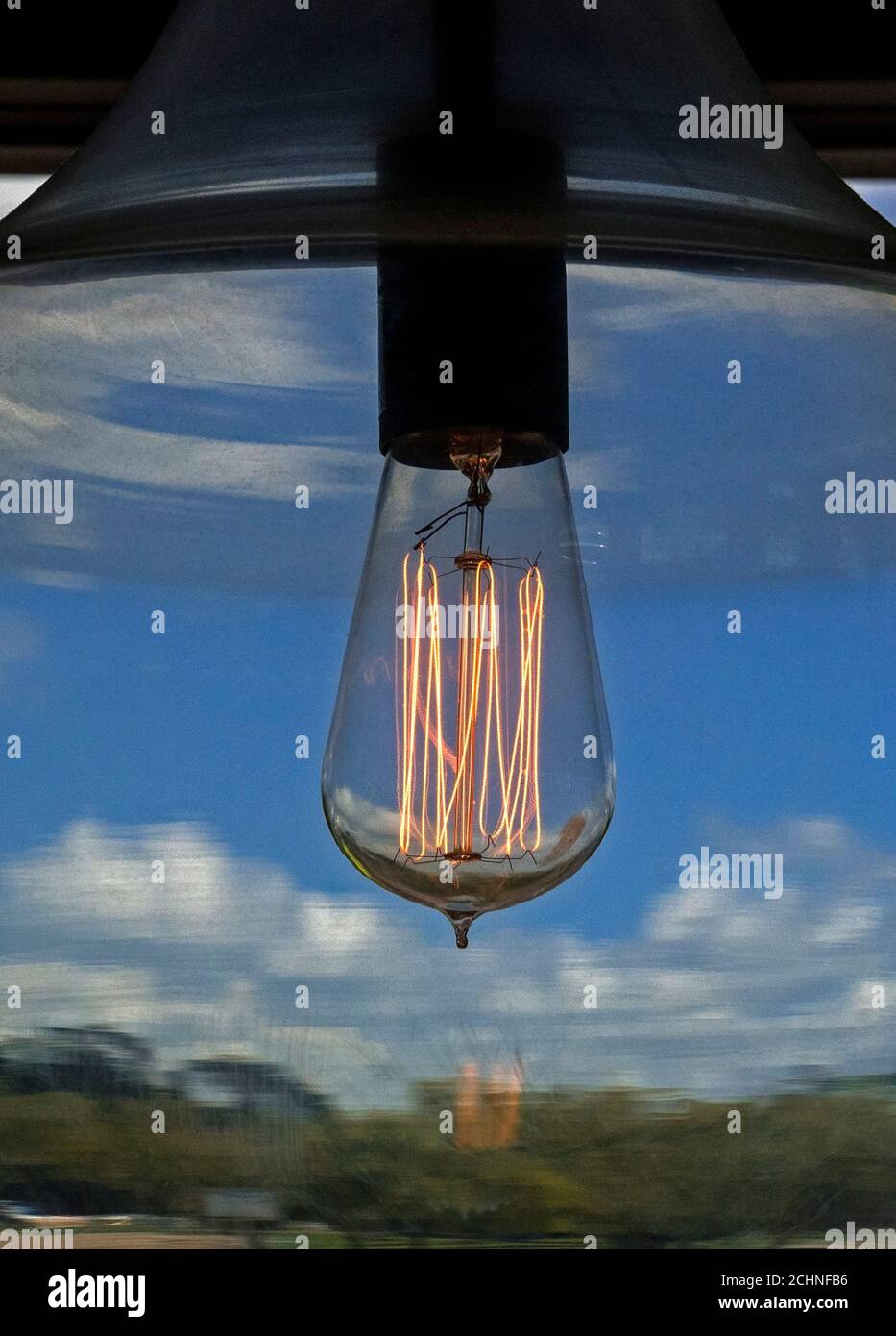 Von Thomas Edison inspirierte Glühbirne im Retro-Look erstrahlt in einem Restaurant durch einen hängenden Globus. Stockfoto