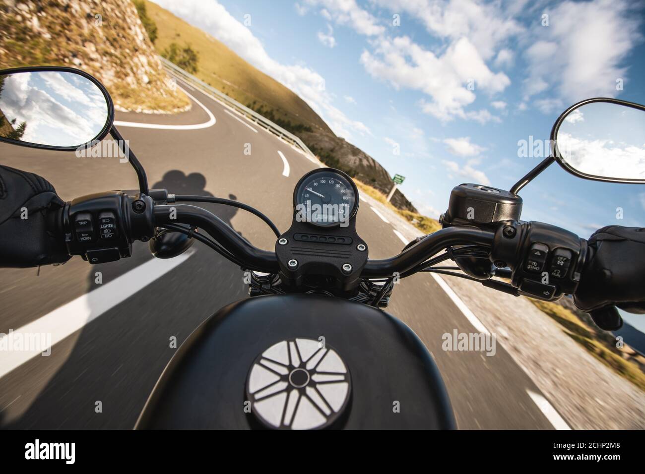 Fahrer, der Motorrad auf einer Asphaltstraße in den Bergen fährt, Detail der Lenkstange. Stockfoto