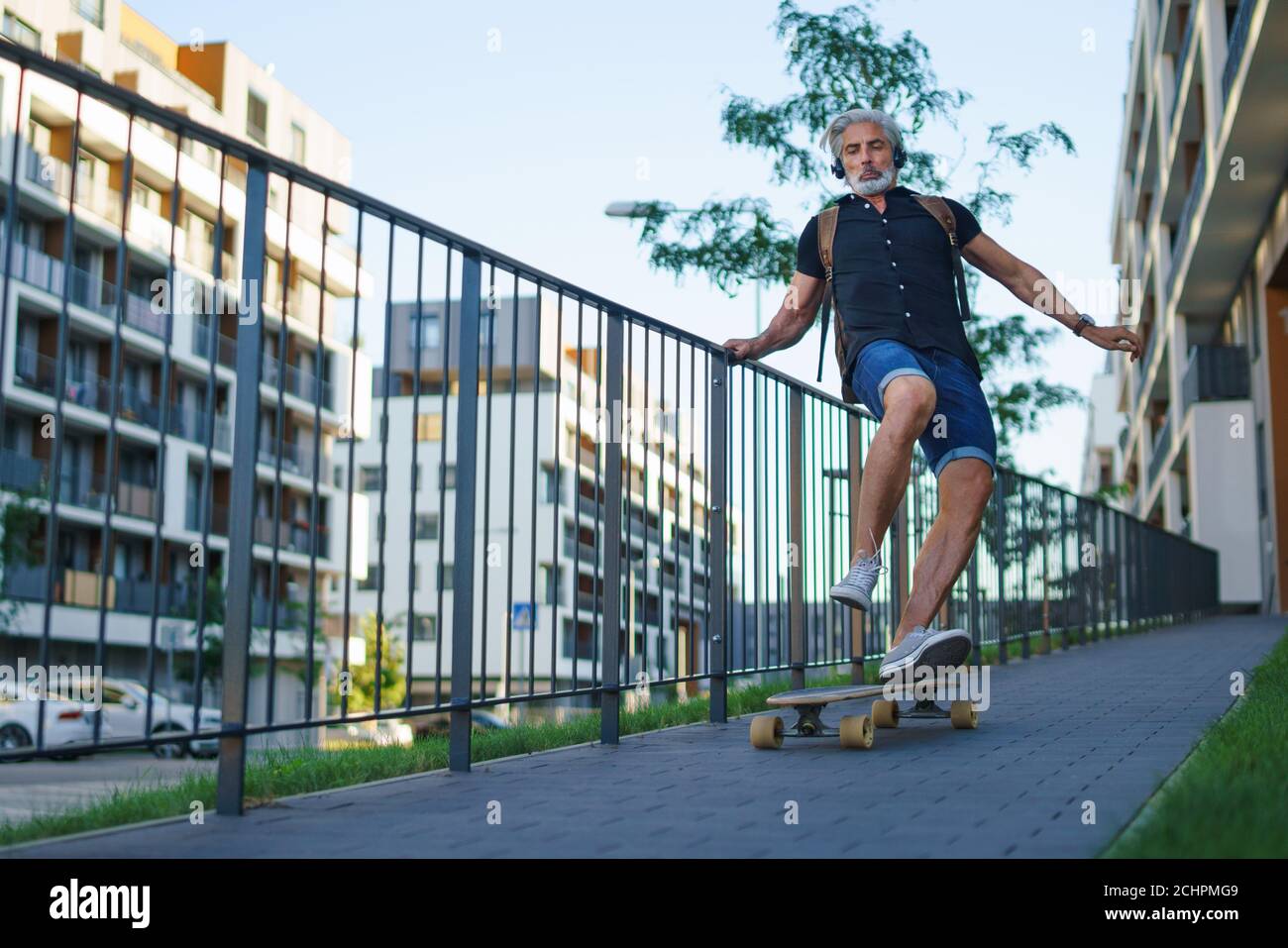 Portrait von reifen Mann Reiten Skateboard im Freien in der Stadt, gehen zurück zur Arbeit. Stockfoto