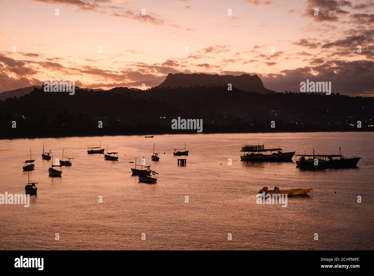 BARACOA, KUBA - CA. JANUAR 2020: Bucht von Baracoa und Boote bei Sonnenuntergang. Stockfoto