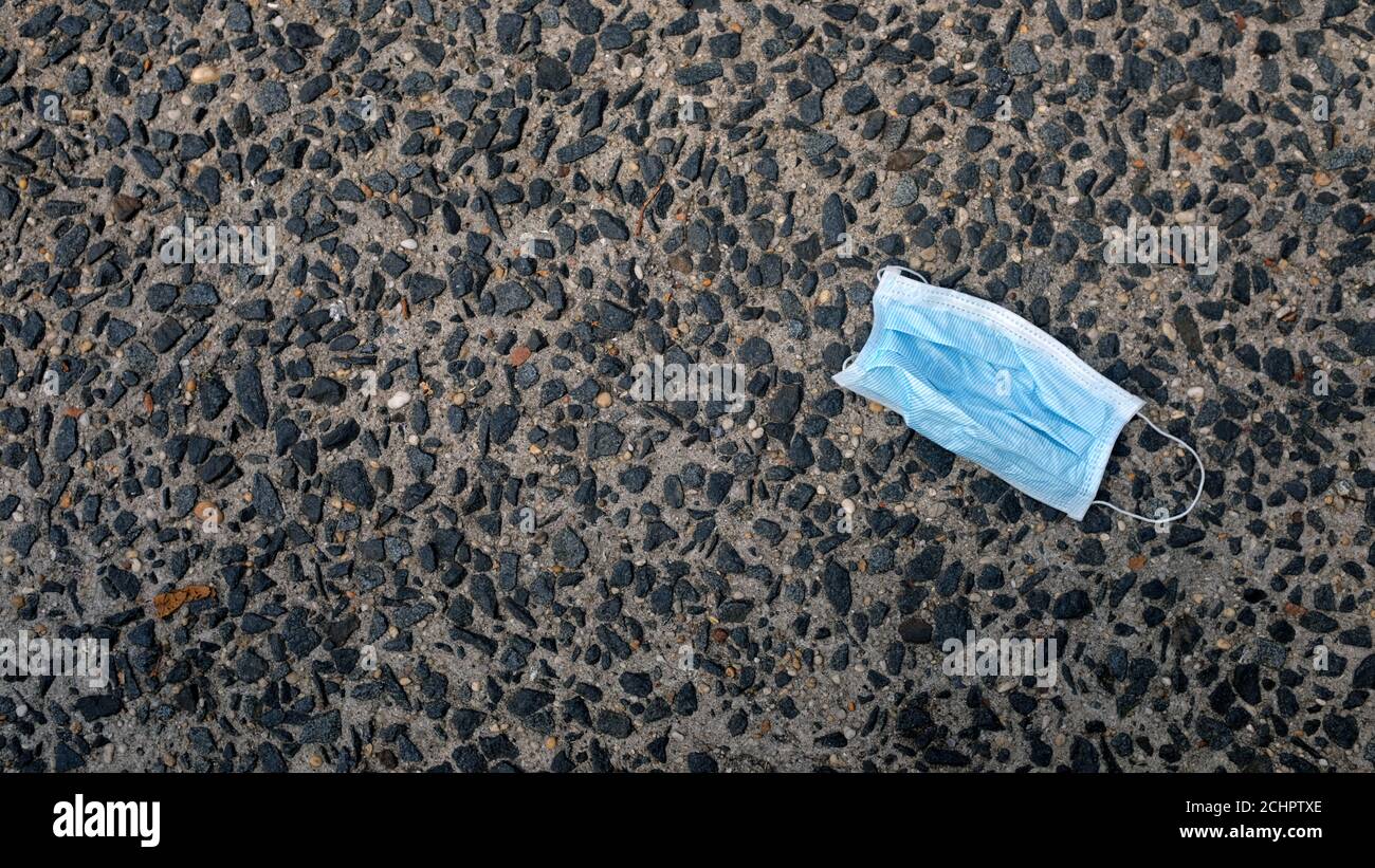 Blaue Einweg-FASK-Maske auf dem Boden entsorgt Stockfoto