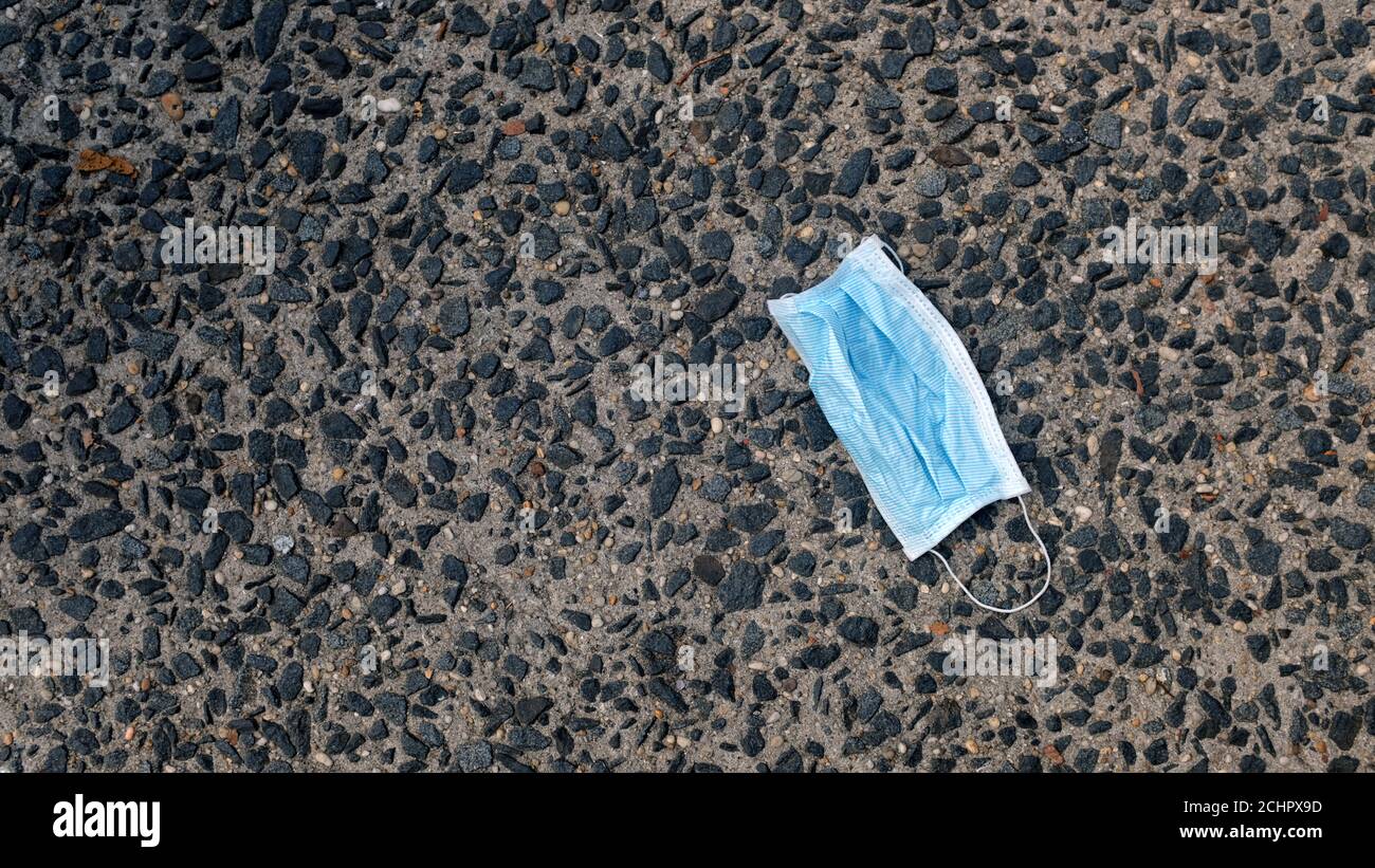Blaue Einweg-Gesichtsmaske auf dem Boden entsorgt Stockfoto