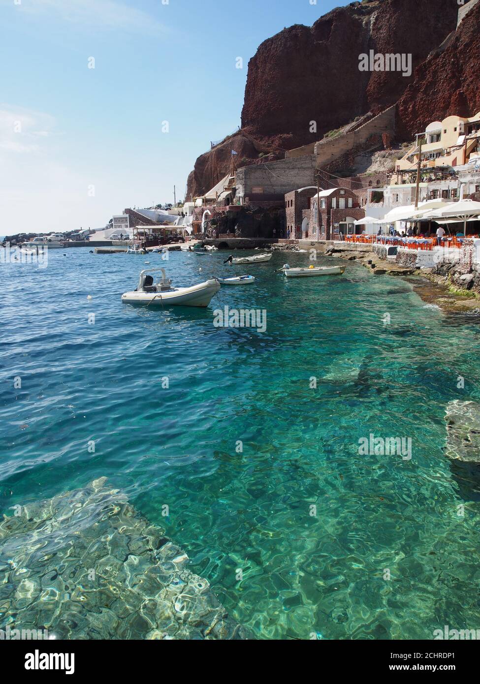 Boote, die im klaren Meer der Bucht von Amoudi vor dem klaren blauen Himmel, Oia, Santorini, festgemacht sind Stockfoto