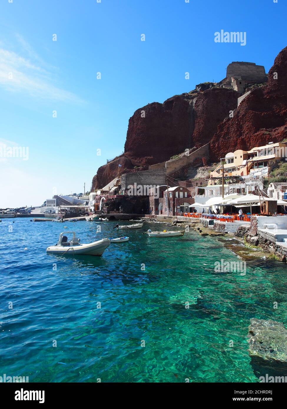 Boote, die im klaren Meer der Bucht von Amoudi vor dem klaren blauen Himmel, Oia, Santorini, festgemacht sind Stockfoto