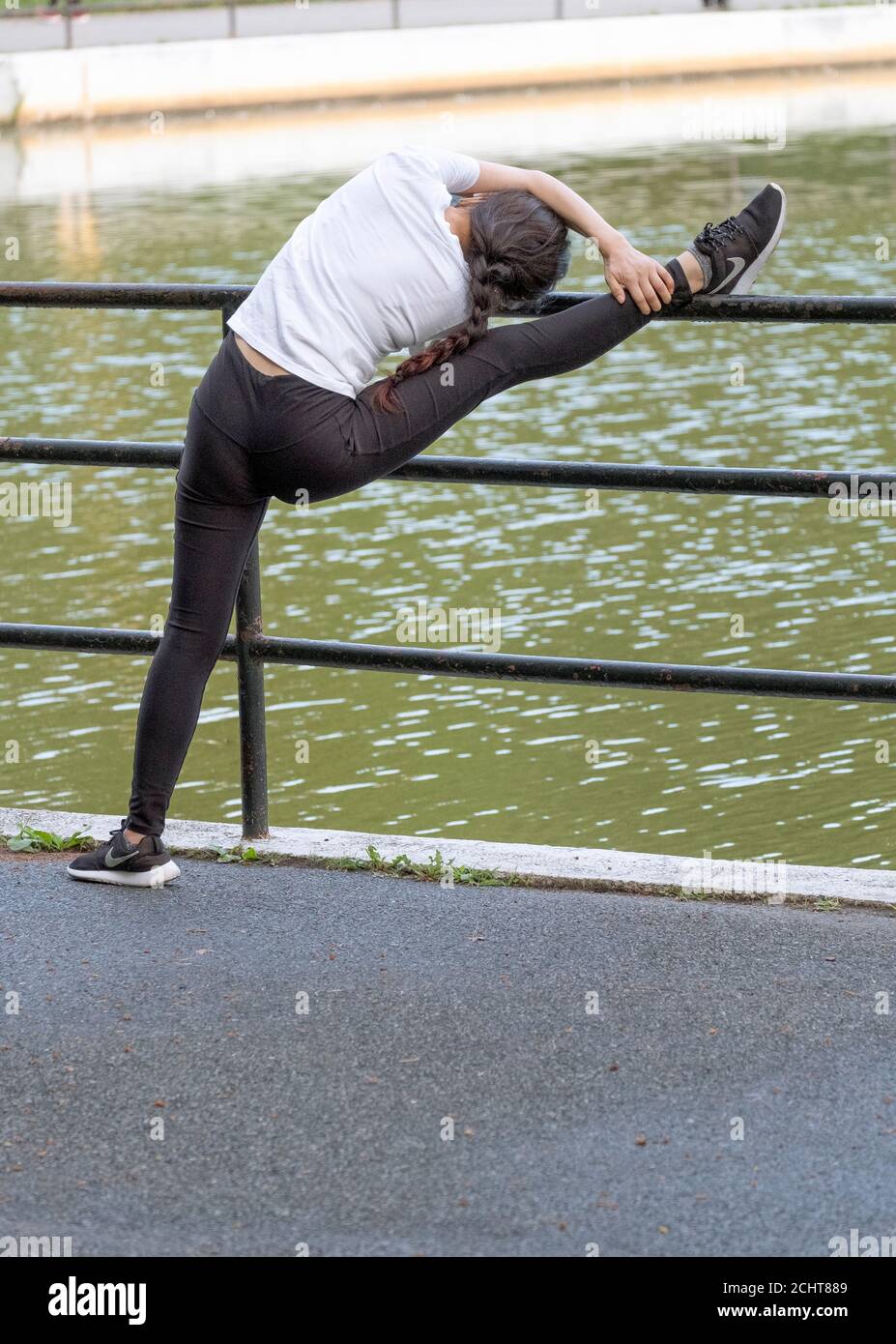 Eine sehr limber & flinke asiatische amerikanische Frau dehnt sich vor dem Training. In Kissena Park, Flushing, New York City. Stockfoto
