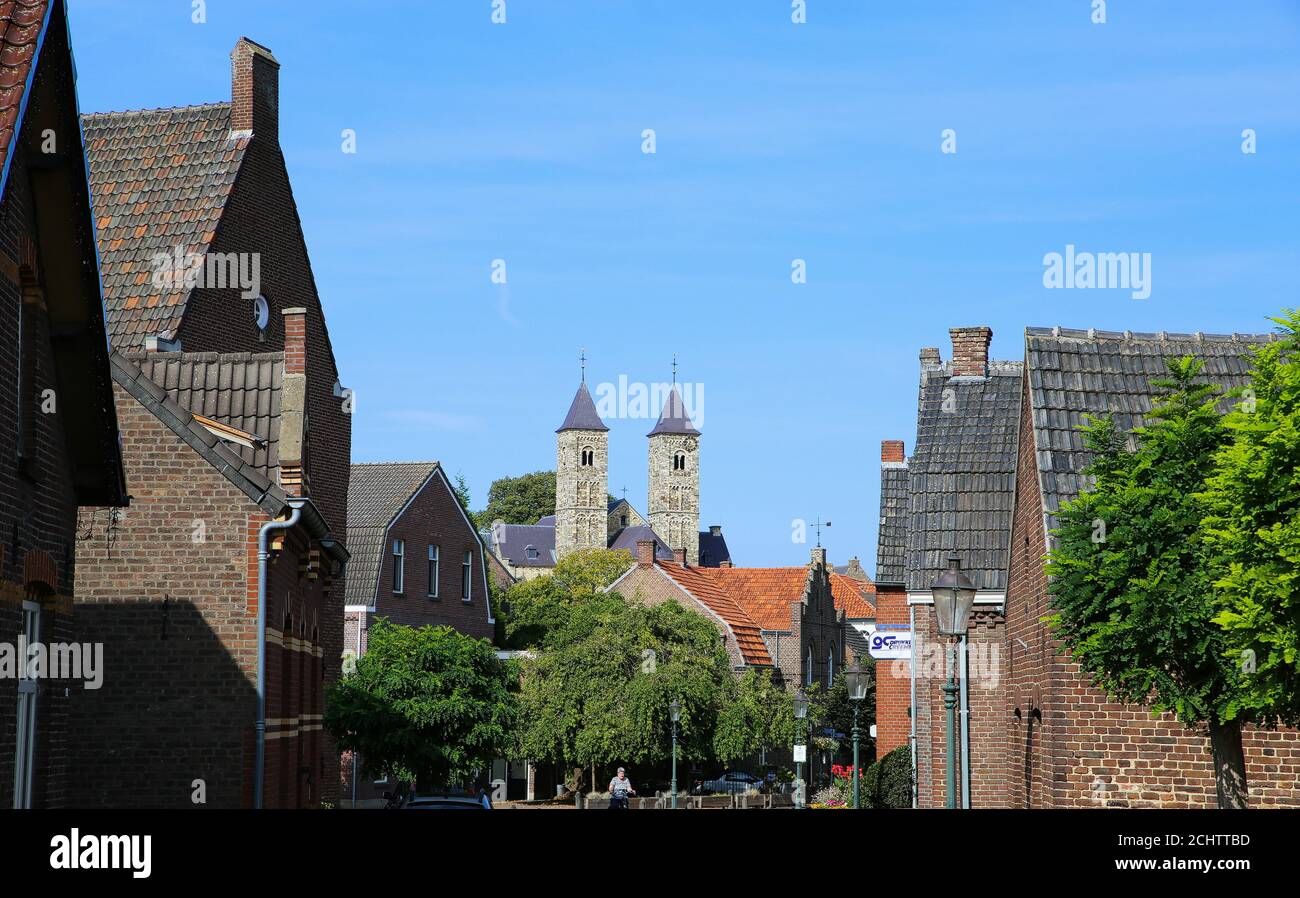 Sint Odilienberg, Niederlande - 9. August 2020: Blick über die Straße hinter den Häusern auf die römische Basilika aus dem 11. Jahrhundert gegen den blauen Himmel im Sommer Stockfoto