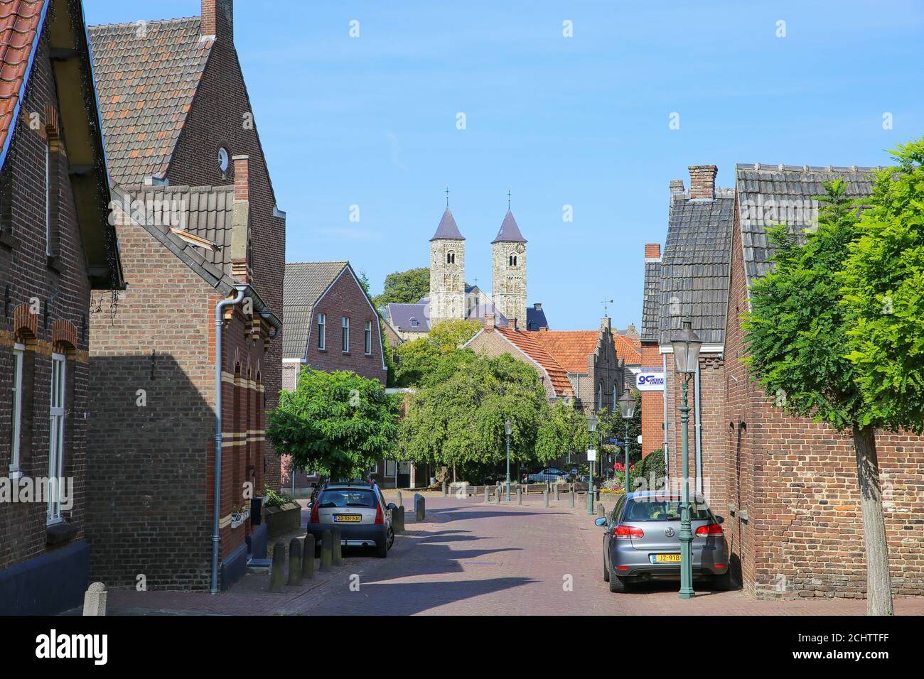 Sint Odilienberg, Niederlande - 9. August 2020: Blick über die Straße hinter den Häusern auf die römische Basilika aus dem 11. Jahrhundert gegen den blauen Himmel im Sommer Stockfoto